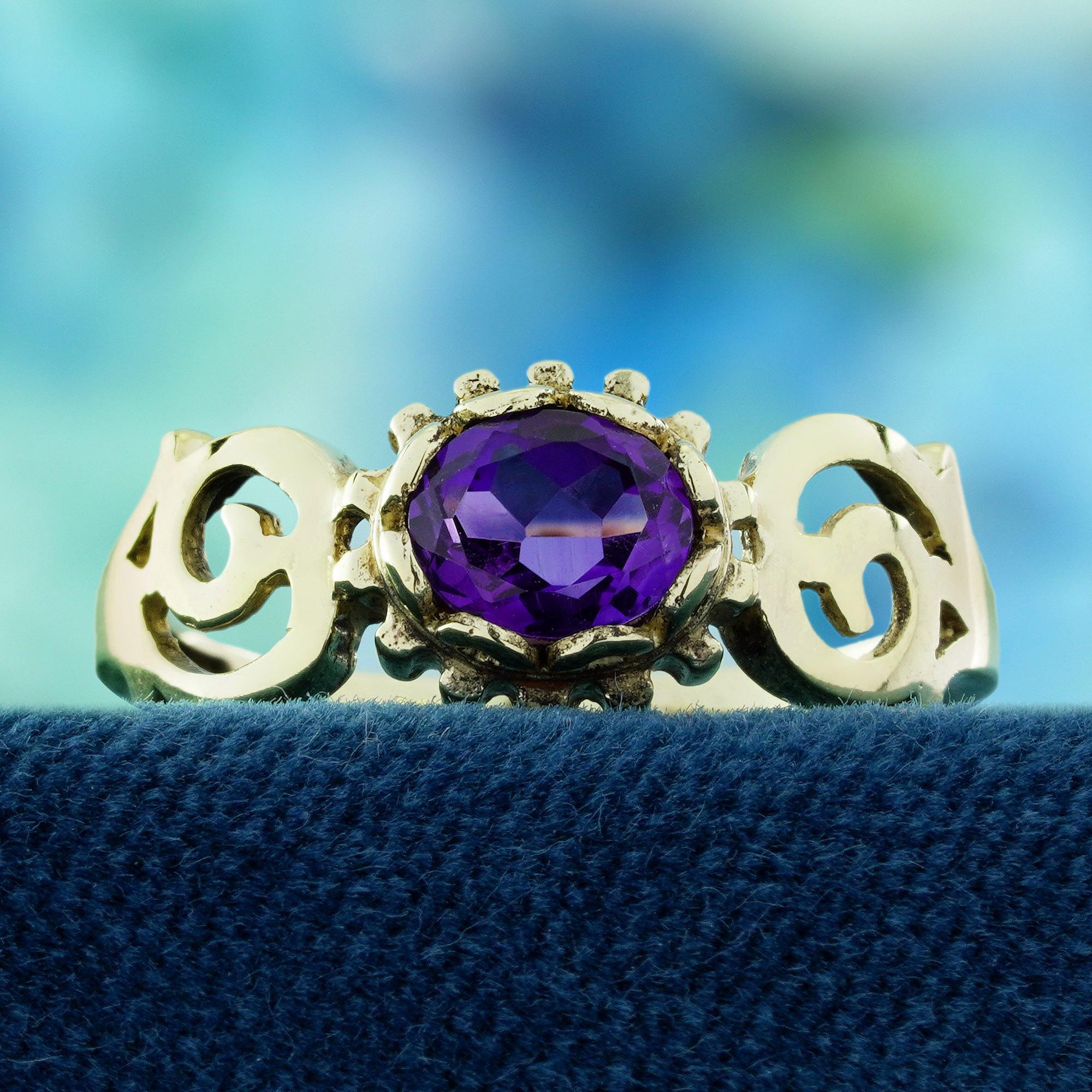 Une améthyste ovale vibrante trône gracieusement au centre, fixée dans une monture classique qui met en valeur sa riche teinte violette. Les épaules sont ornées de filigranes floraux circulaires complexes, ajoutant une touche de charme vintage et de