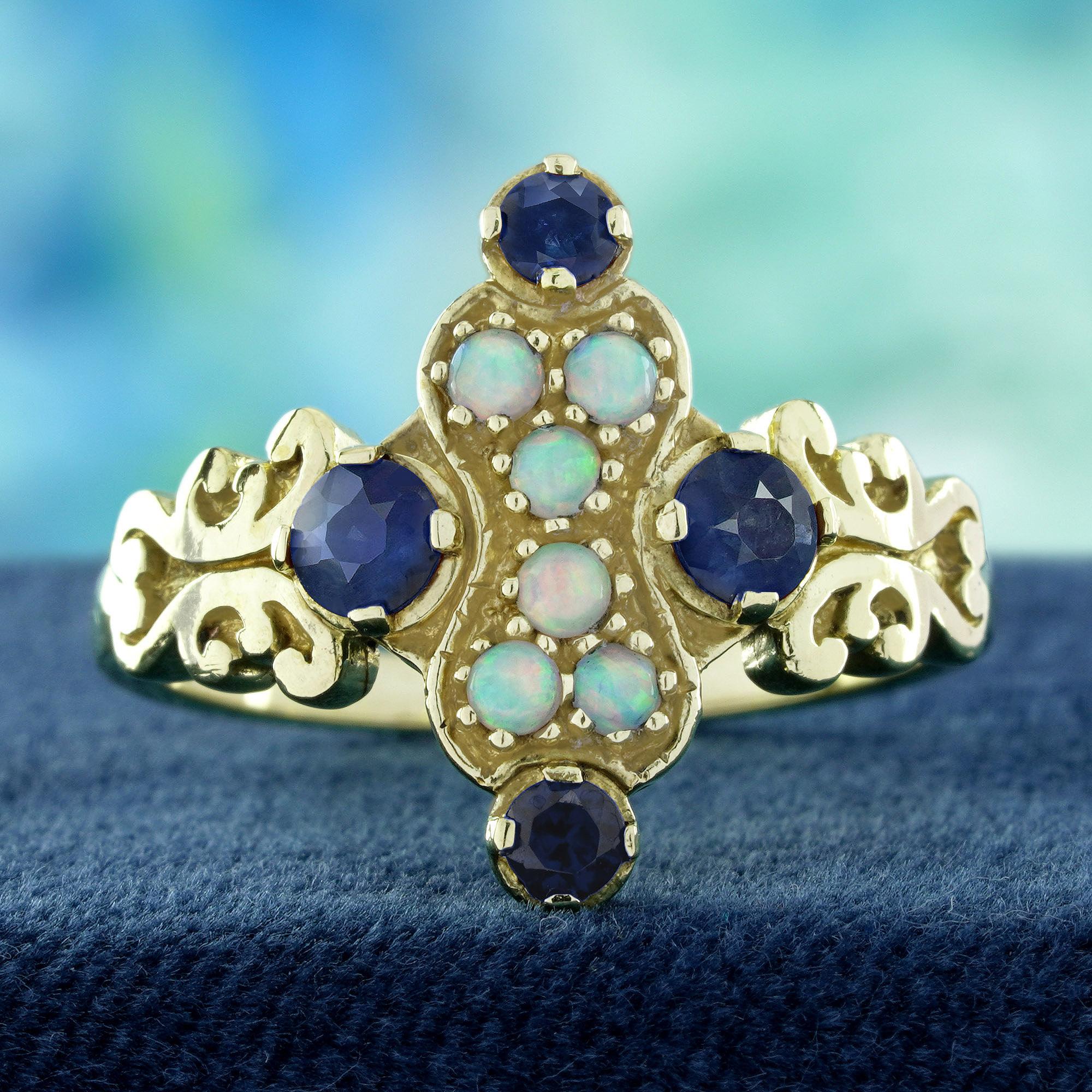 Un gruppo di opali naturali rotondi incastonati al centro, circondati da vibranti zaffiri blu rotondi in montatura. Le spalle presentano un'intricata lavorazione in filigrana di ispirazione floreale, che aggiunge un delicato fascino vintage ed