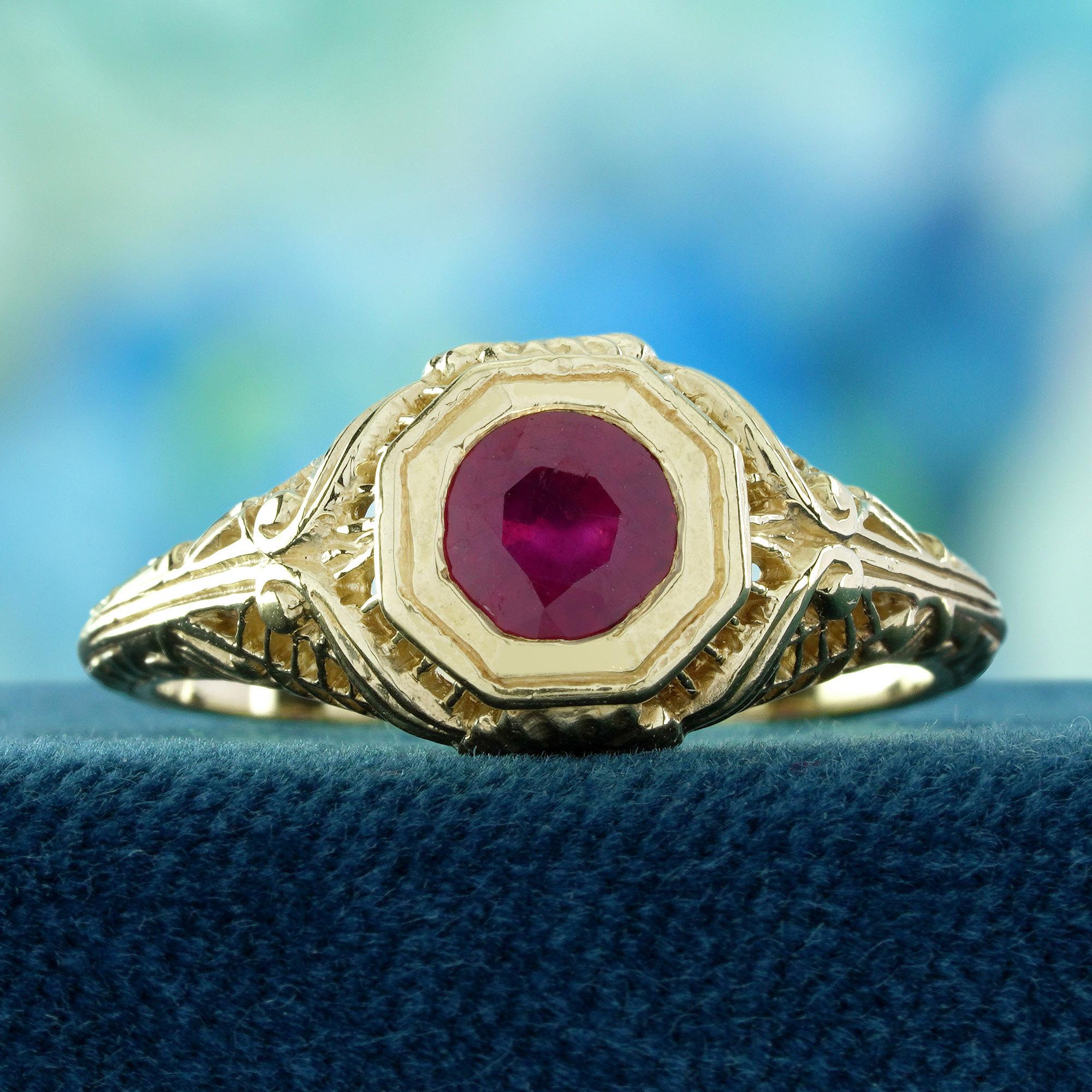 Un vibrante rubino rotondo si trova orgogliosamente al centro, fissato in una montatura classica che mette in risalto la sua ricca tonalità rossa. Le spalle sono ornate da un'intricata filigrana a motivi floreali, che aggiunge un fascino romantico e