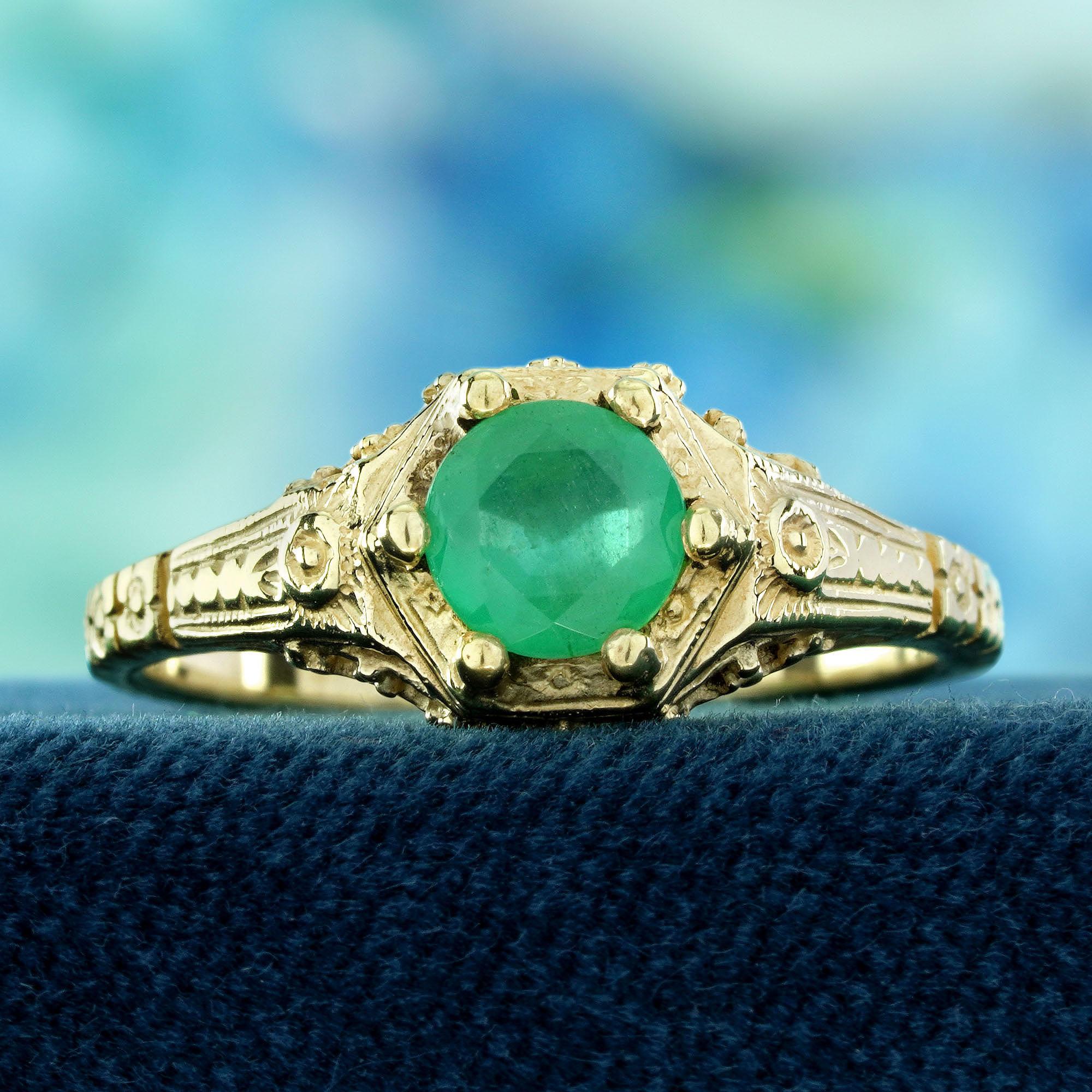 Prova l'eleganza classica con questo anello con smeraldo rotondo in stile vintage. Un radioso smeraldo rotondo è al centro della scena, circondato da splendidi disegni floreali sulle spalle che ne esaltano il fascino senza tempo. I dettagli