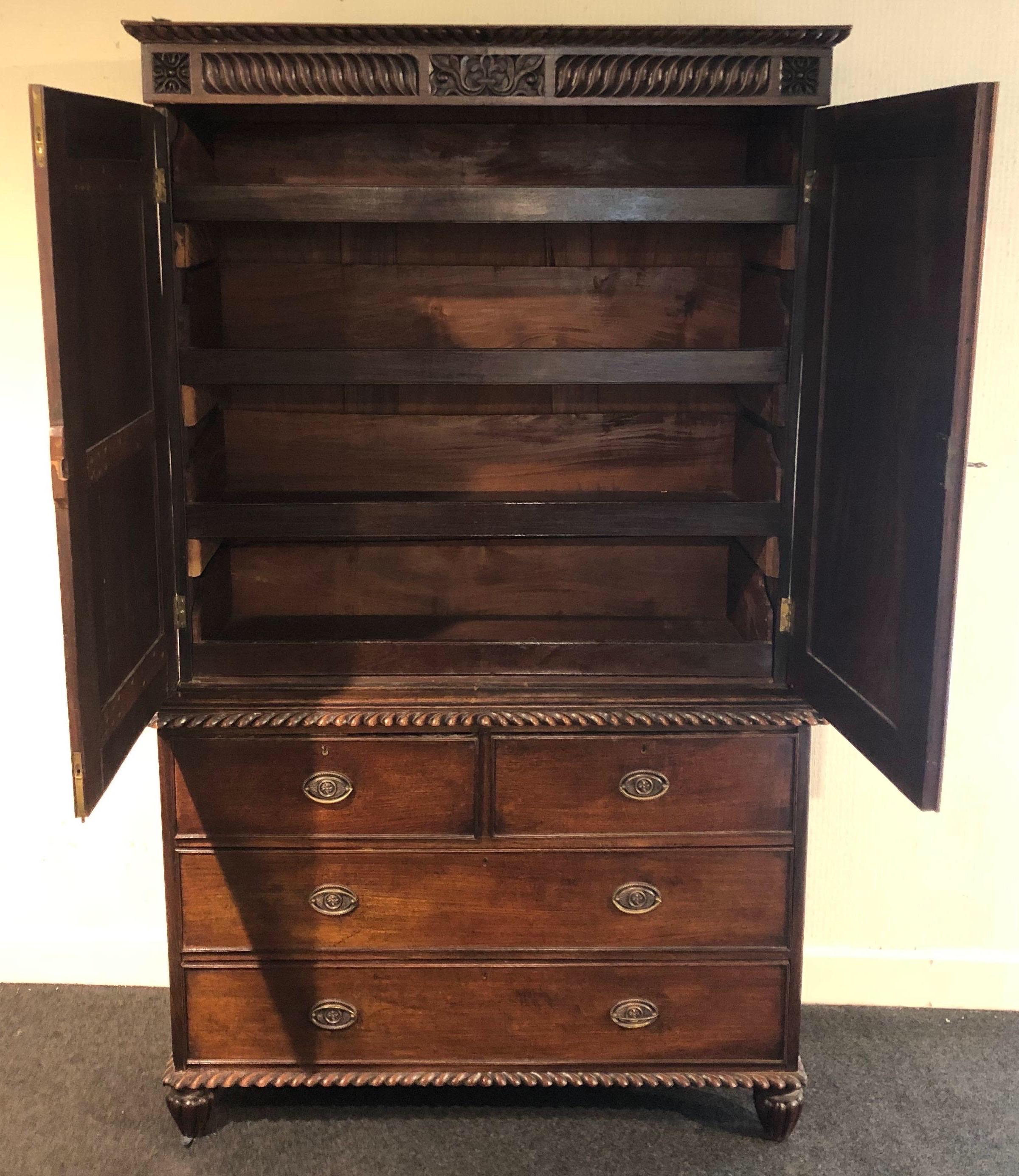 19th century Anglo Indian linen press. All carved rosewood. Two carved door panels open to 4 sliding shelves, resting on a base with carved gadrooning and 2 small drawers over 2 larger drawers.