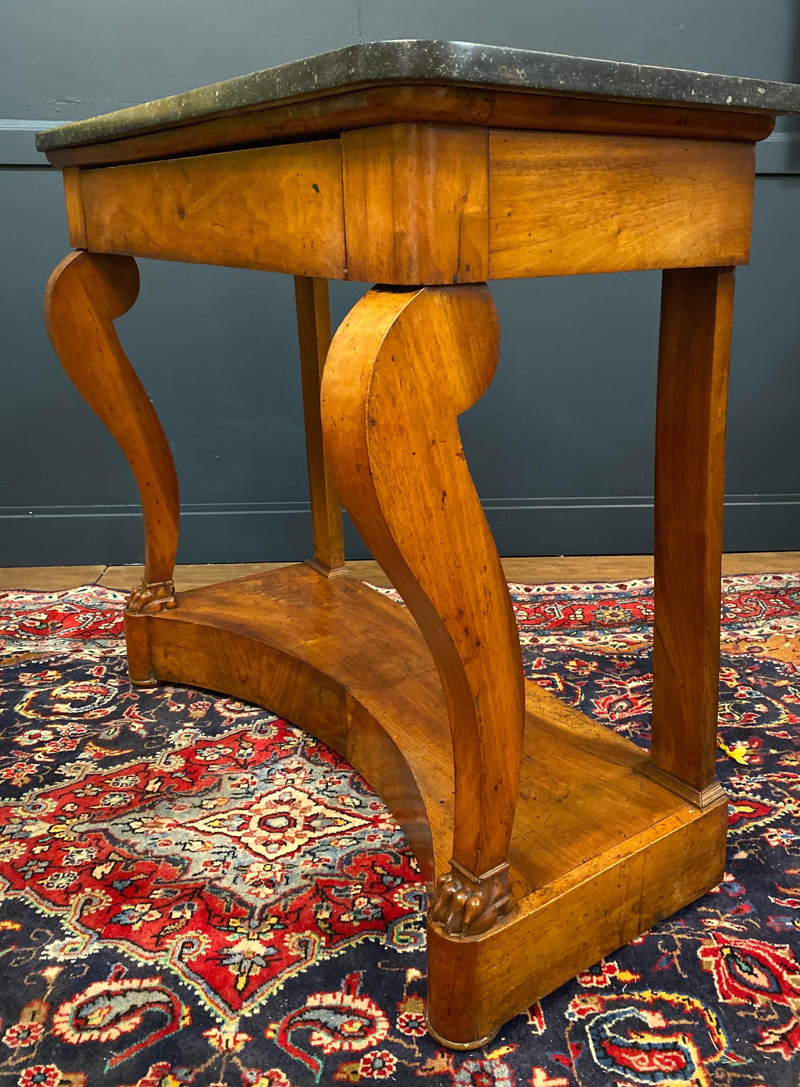Late 19th century mahogany console table with a black marble rounded corner top.
This marble-top console table is resting on two straight legs in the back, and two front scrolled legs ending with paw feet.