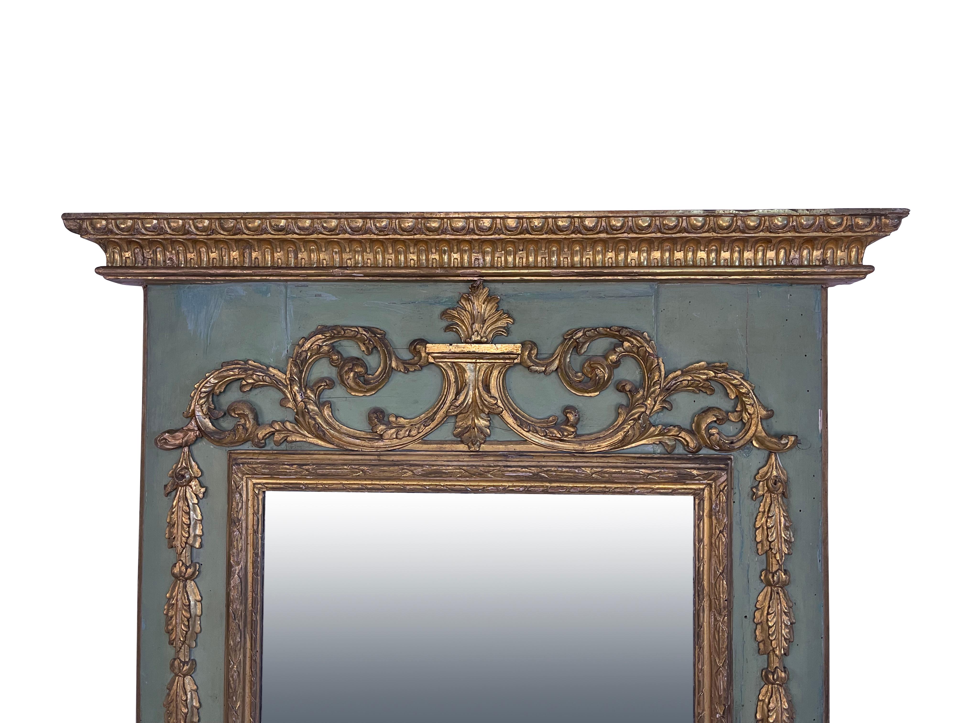 Lovely teal green/blue painted European 19th century Mirror with original glass and gilt wood decoration throughout. A heavily carved cornice with dart and eg and foliate design with a central pediment with flame and heavy scroll decoration with