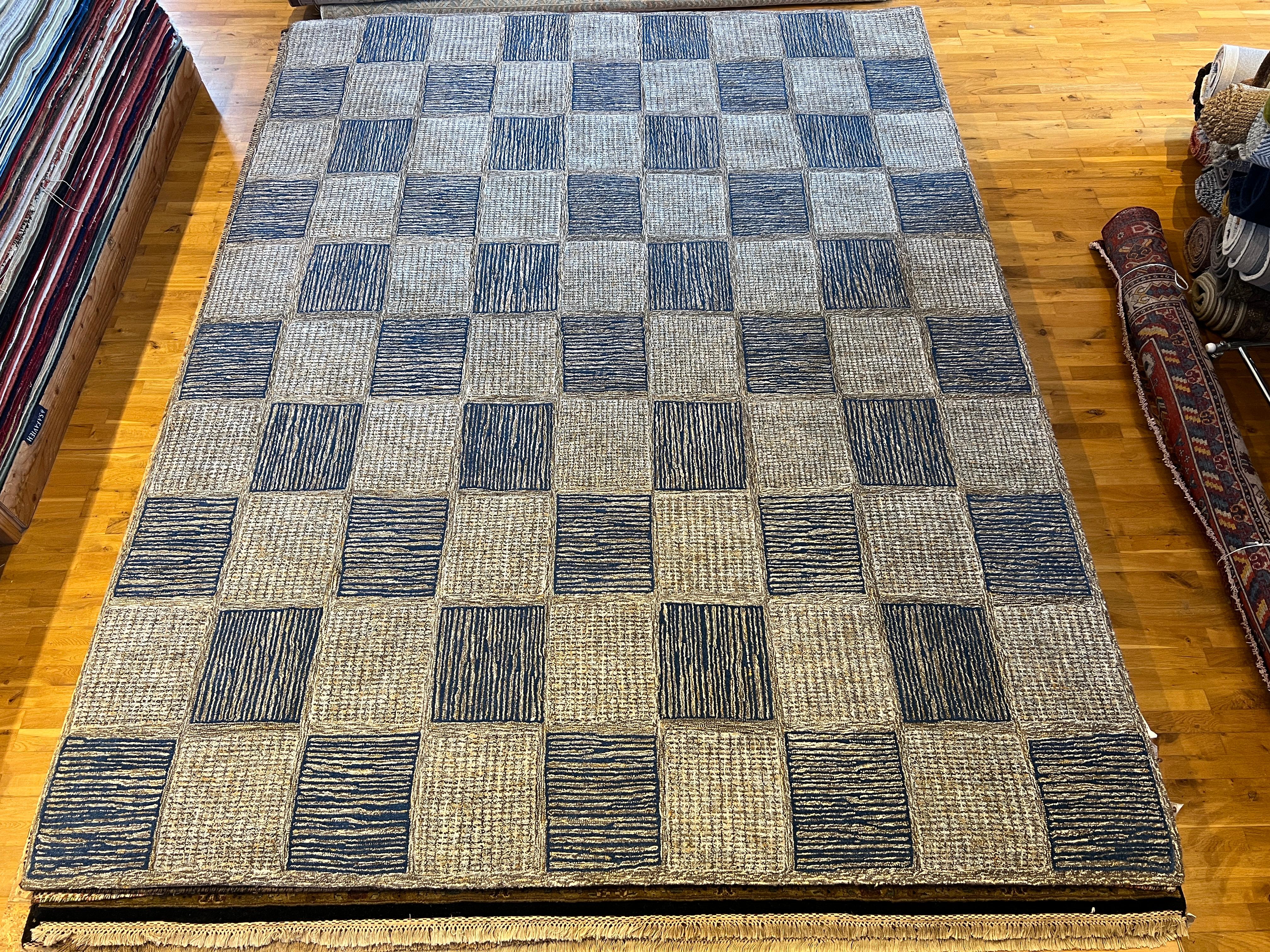 Revive your home decor with our 9'x12' blue grey checkered rug! Hand-tufted with all wool, this modern piece adds a touch of elegance and comfort to any room. Its versatile design and quality material offer lasting durability and style. Elevate your