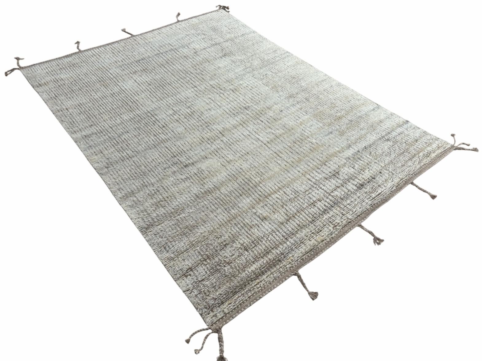Eleva tu espacio vital con el exquisito encanto de esta nueva y moderna alfombra de diseño bereber marroquí Beni Ourain anudada a mano, elaborada con precisión y cuidado a partir de 100% lana. Combinando el encanto del estilo marroquí con la