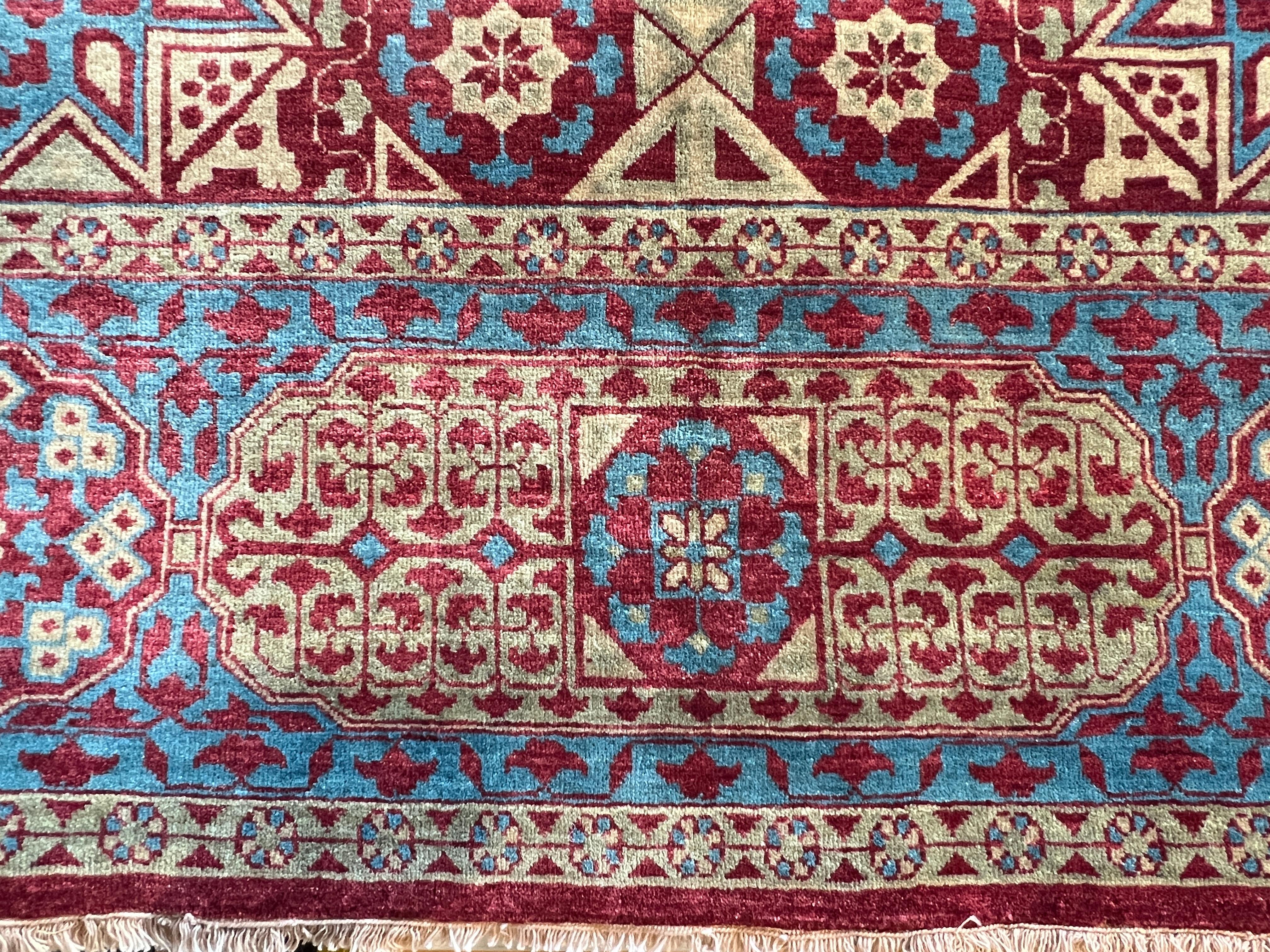 Eleva il tuo spazio con il nostro tappeto 9'x12' dal design persiano in rosso tenue, blu e oro, interamente annodato a mano in lana e prodotto in Pakistan. Caratterizzato da un fantastico design di transizione, questo tappeto aggiunge stile e