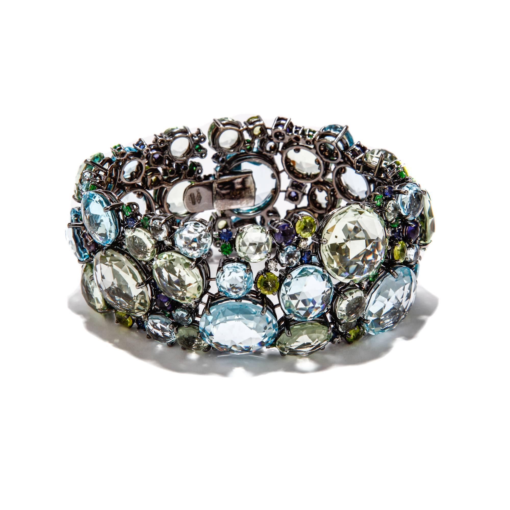 This A & Furst bracelet features 181.12 ct. of prasiolite (green quartz), blue topaz, peridot, iolite, tsavorite garnet, blue sapphires, and peridot with 0.65 ct. of diamonds set in 18k white gold plated with black rhodium. A & Furst jewelry is