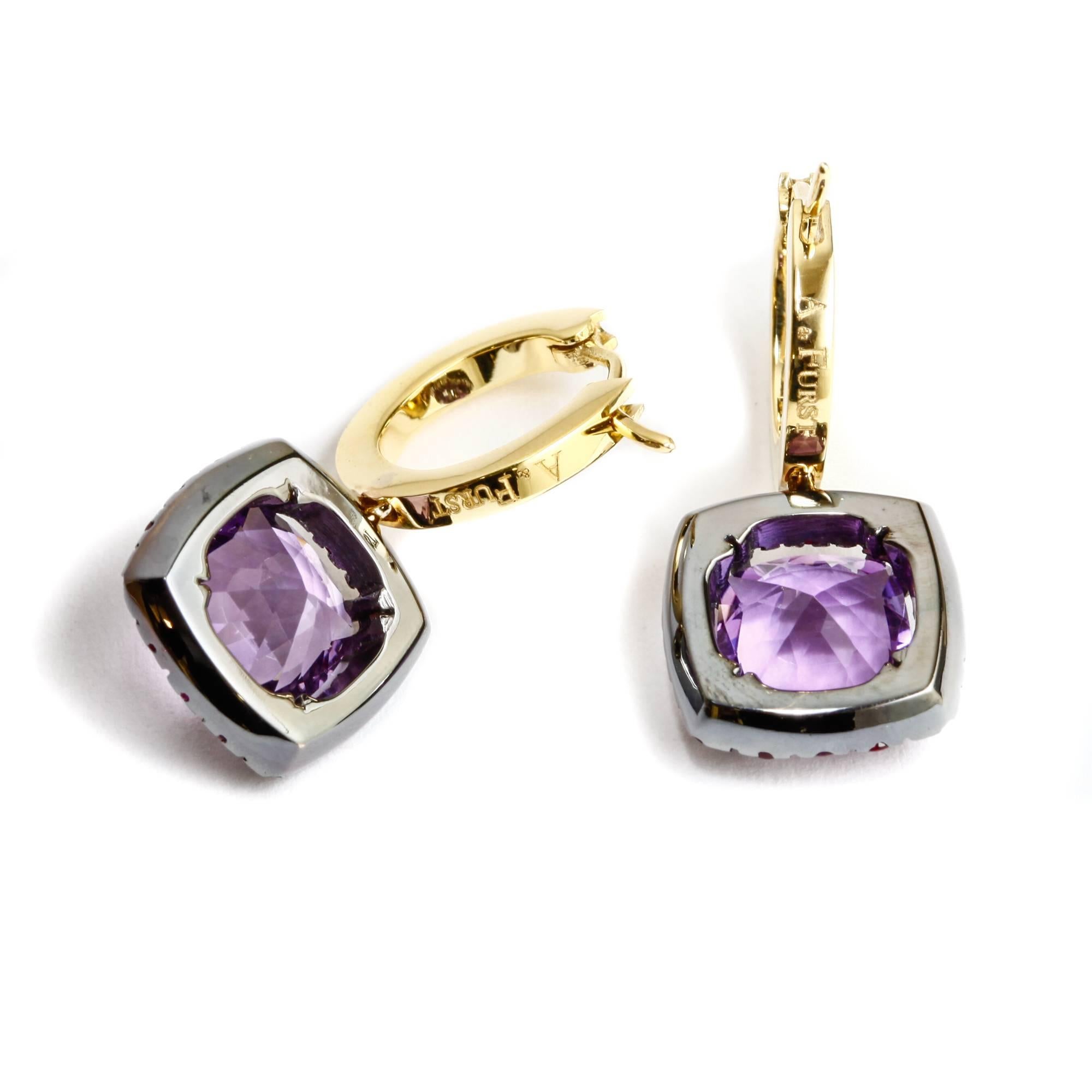 These A & Furst drop earrings feature 3.00 ct. total of square cushion cut amethysts surrounded by a halos made of 0.91 ct. total round rubies set in 18k black gold. The stones hang from 18k yellow gold huggies. The earrings are in perfect