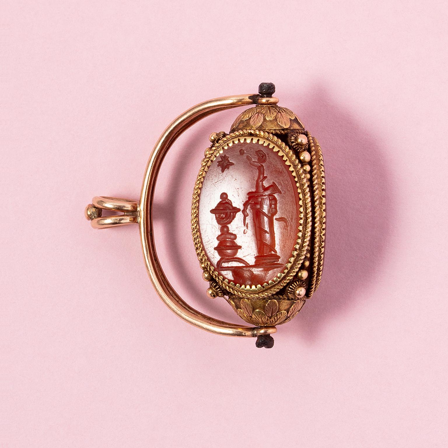 A 14 karat gold rotating seal pendant in a neoclassical style. Three oval cornelian intaglios: one of an allegory of astronomy and two of profiles of bearded scientists.

An allegory in visual art is a symbolic representation where an idea or