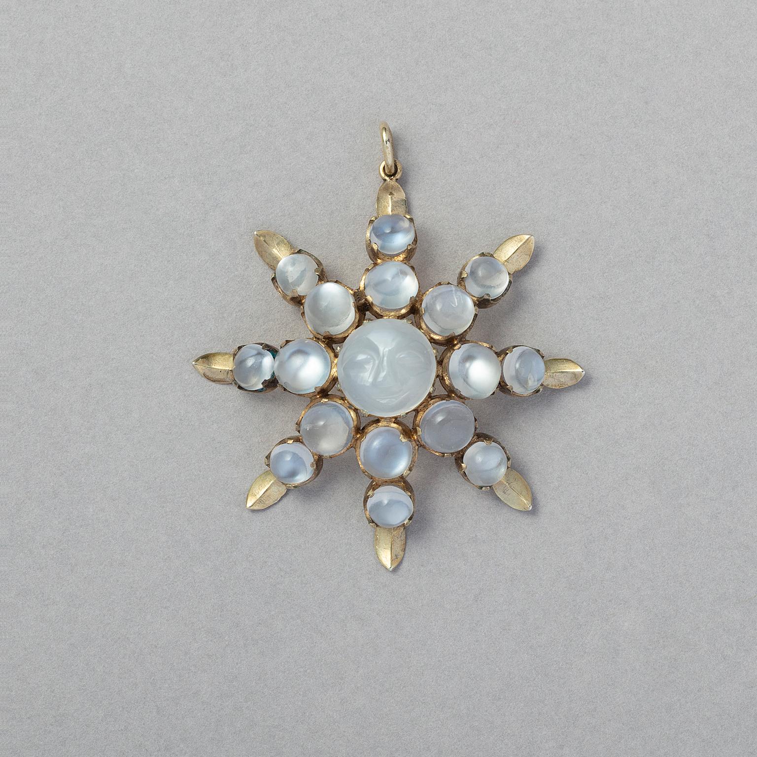 A silver gilt eight-point star pendant, set with two cabochon cut moonstones on each point, descending in size. In the centre a larger round moonstone with a carved smiling face of the 'man in the moon', American, circa 1890.
 
weight: 6.81