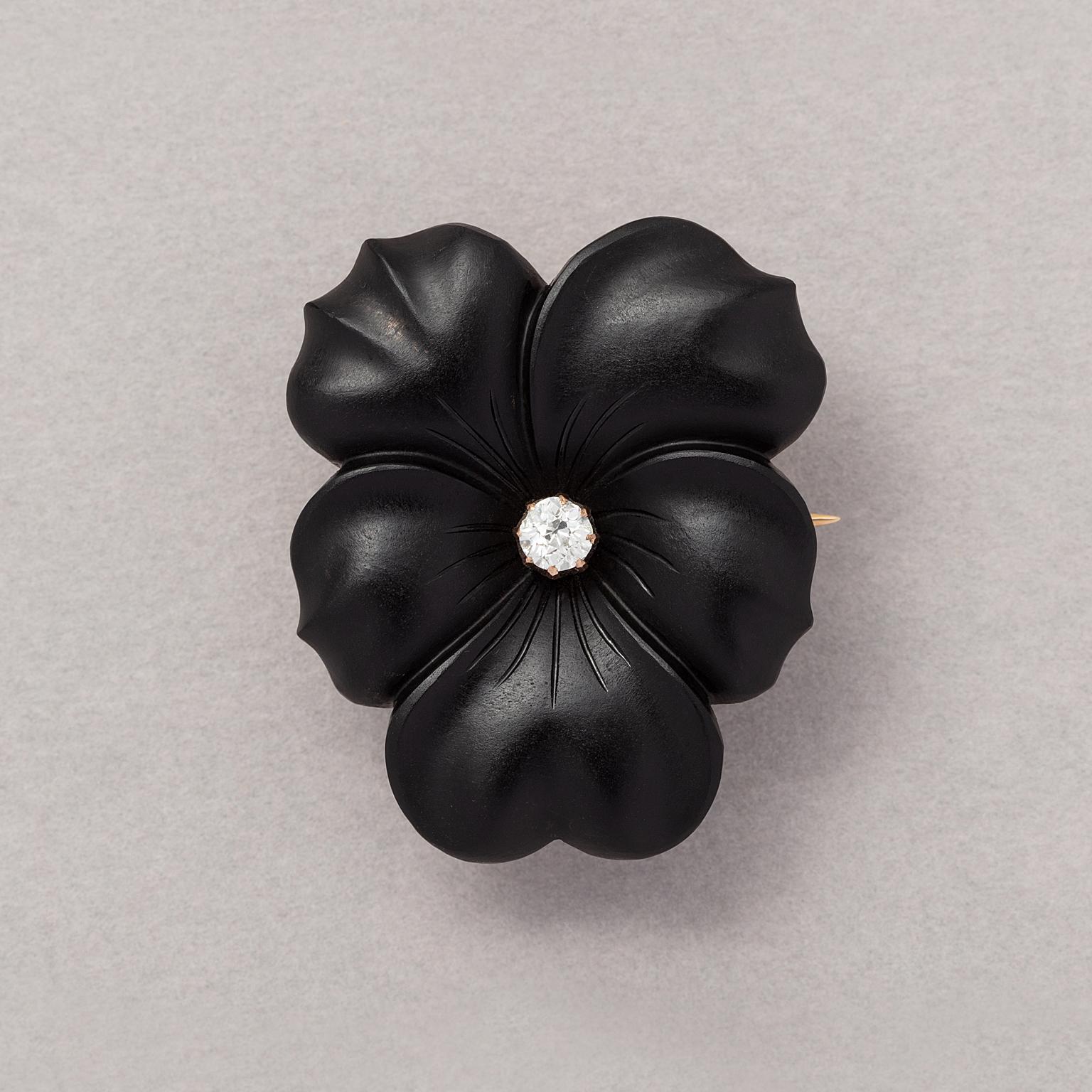 A brooch in the shape of a pansy with a 14 carat gold mounting (and with a metal safety clasp), the flower has been carved from one piece of onyx and is set in the heart with an old cut diamond, circa 1900-1910.

weight: 8.88 grams
dimensions: 3.2 x