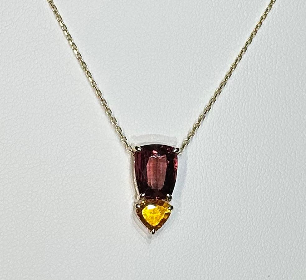 This Pendant is in 14kt Yellow Gold and is set with two unique Sapphires. One is an Iron red Sapphire of 2.89 Carats and is ct into a tapered Rectangle. The other is a Vivid Yellow Triangle cut of 1.22 Carats. Both of these Sapphires are from Sri