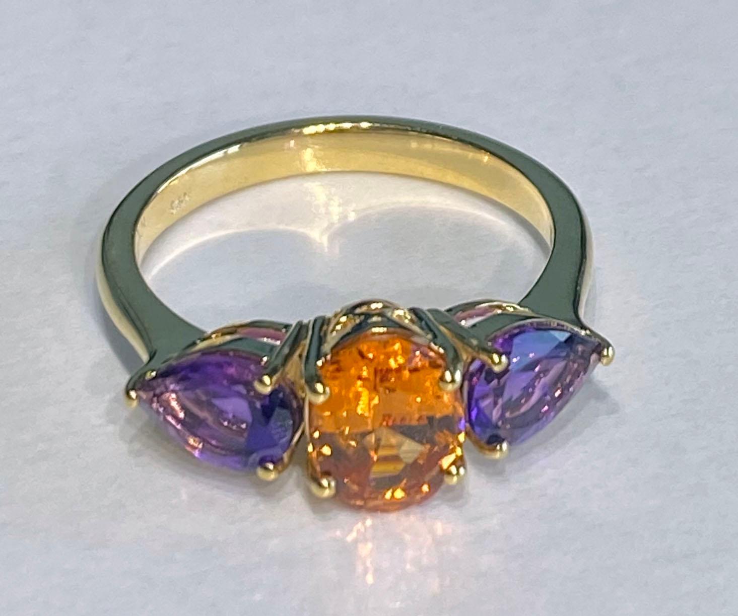 Ein 14kt Gelbgold Ring mit einem Ovalschliff 1,88 Karat Mandarin Granat aus Namibia & 2 Birnenschliff Amethysten von 1,11 Karat zusammen. Das Band ist eine Größe 7 US und die Steine passen als kontrastierende Farben. 
