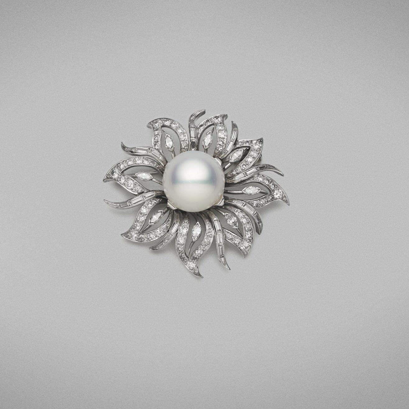 An Australian Cultured South Sea pearl and diamond brooch made in 18ct white gold, set with a button shaped pearl of clean skin and excellent lustre, white in colour with strong pink tones. The brooch is set with round brilliant, baguette and