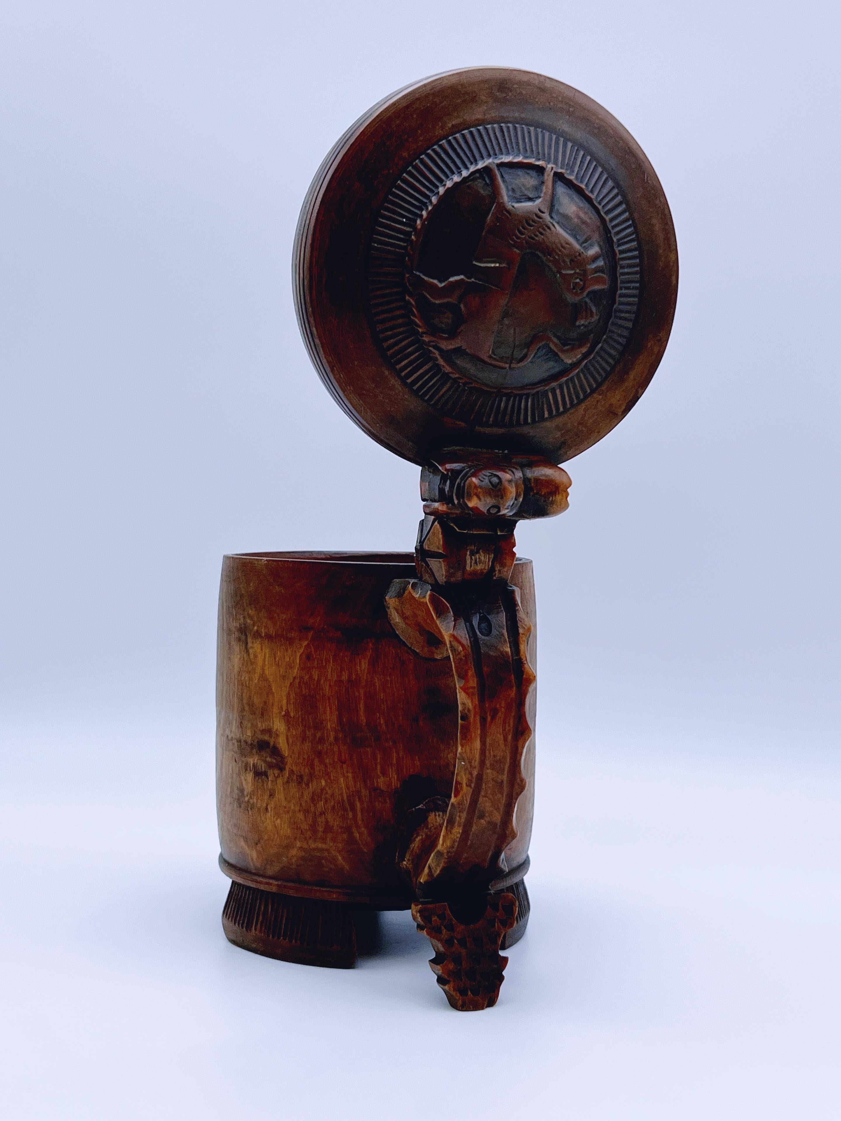 Une rare et exquise chope primitive de Norvège, fabriquée en bois de bouleau / bois dur avec de remarquables détails sculptés à la main. Cette pièce exceptionnelle présente une figurine de lion élégamment perchée au sommet de la poignée, complétée