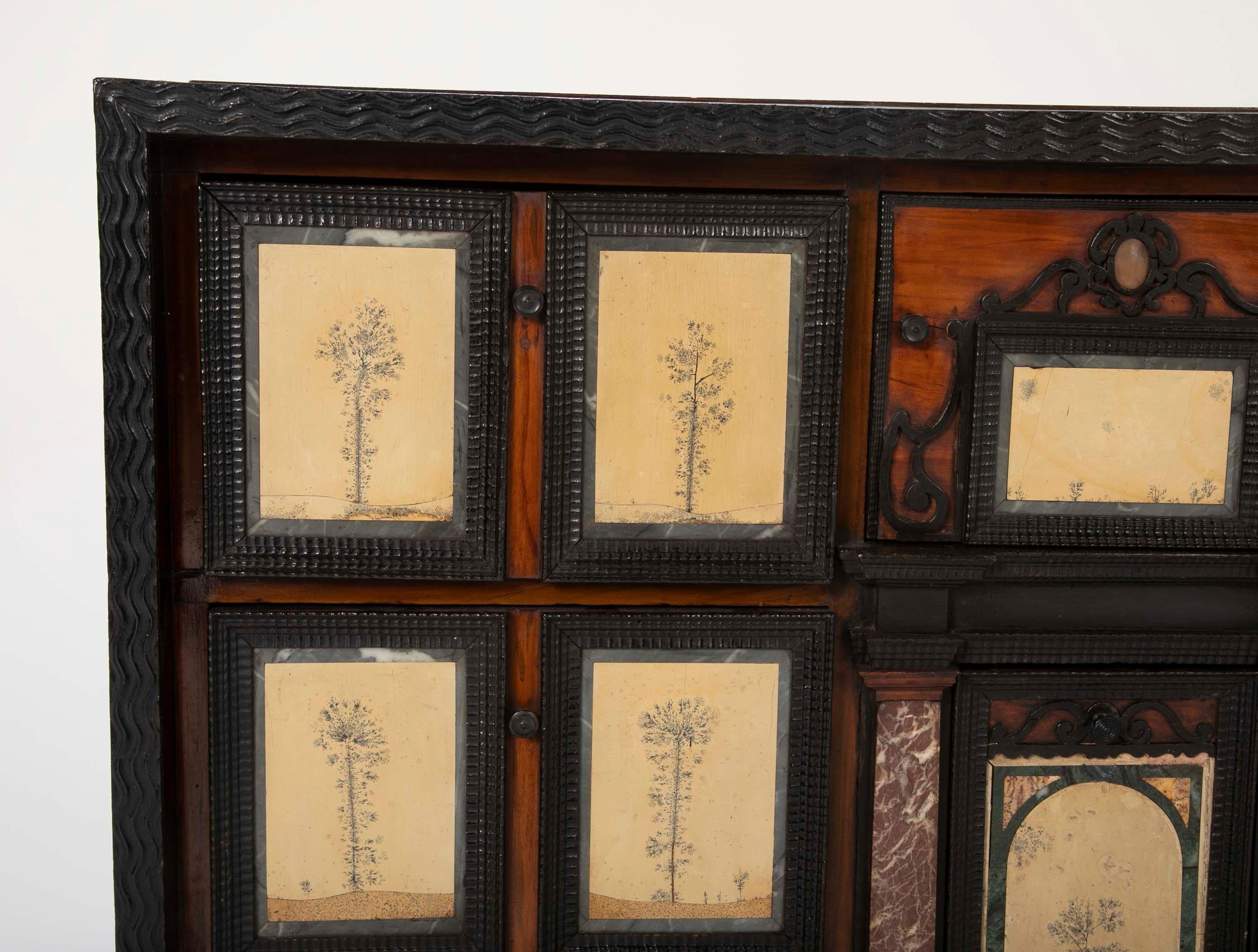 A 19th century Italian Vargueno having Pietra Dura panels as drawer front depicting landscapes made out of marble and Dendritic Limestone. Walnut cabinet body surrounded by ebonised ripple 