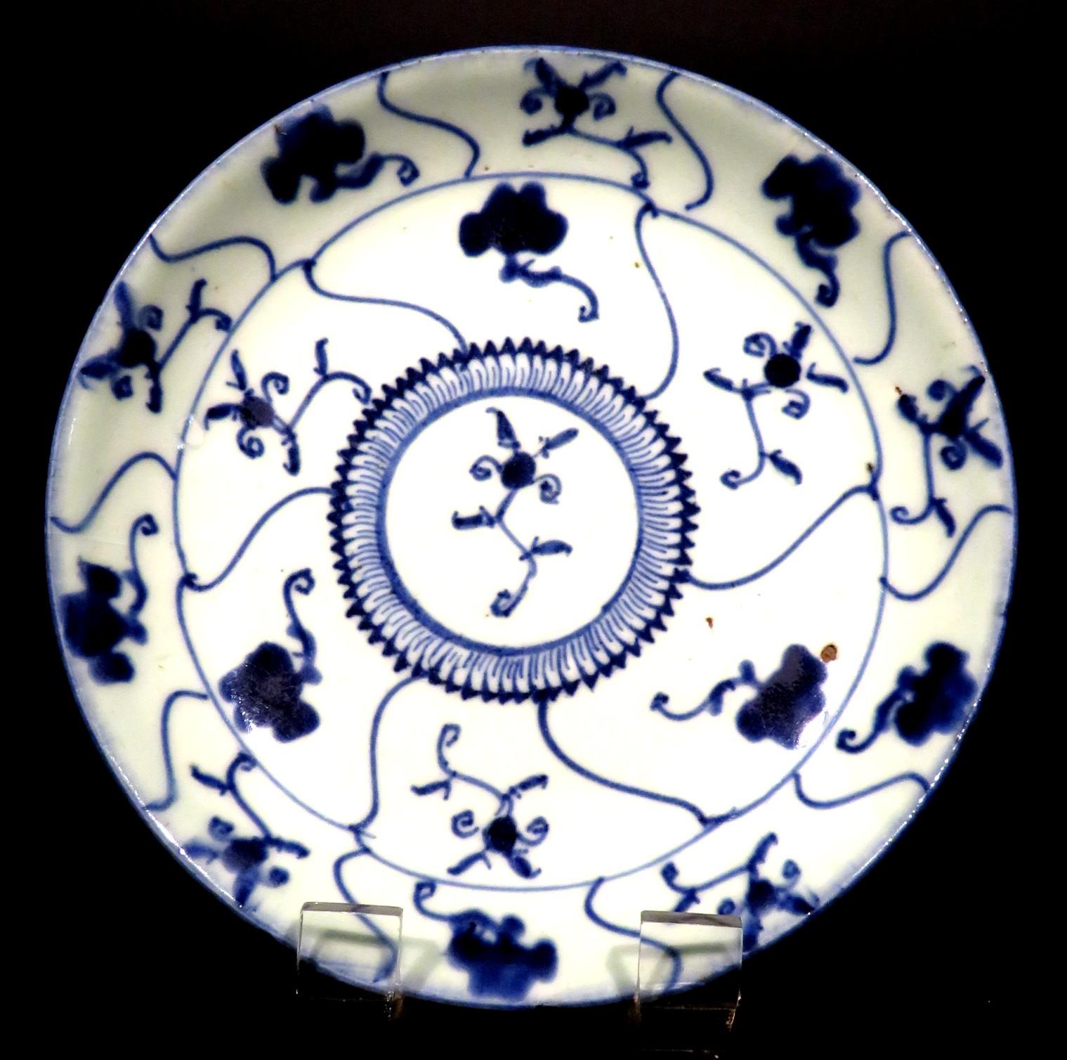The central field showing a medallion of overlapping petal motifs, radiating out to auspicious Chou character (twisted peach tree) & lotus blossom designs, segmented by undulating linear & flower blossoms designs.        The underside showing a