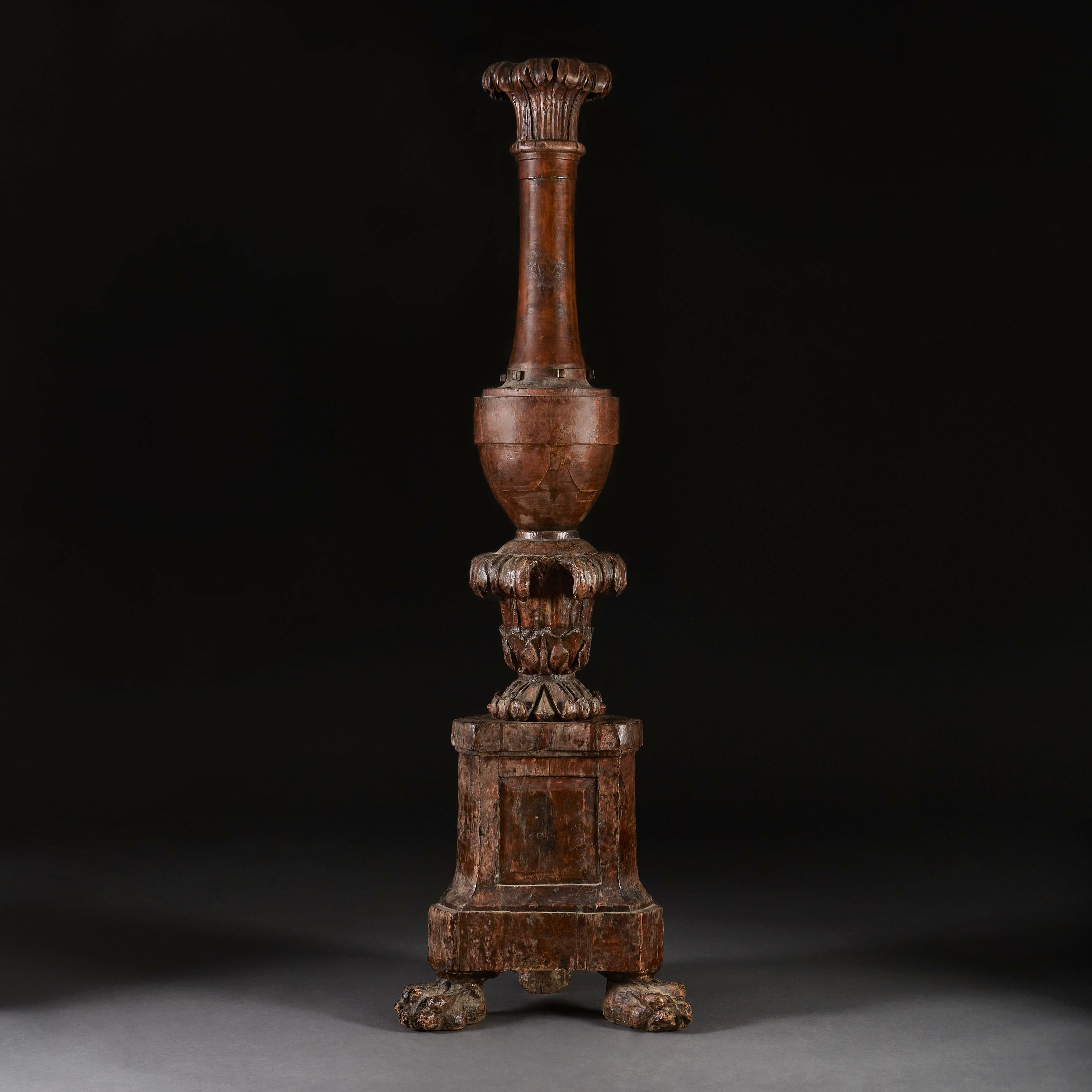 A mid seventeenth century carved walnut torchere of large scale, with three hairy paw feet, with carved acanthus leaves to the central section, and scrolling palm fronds to the capitol.

  