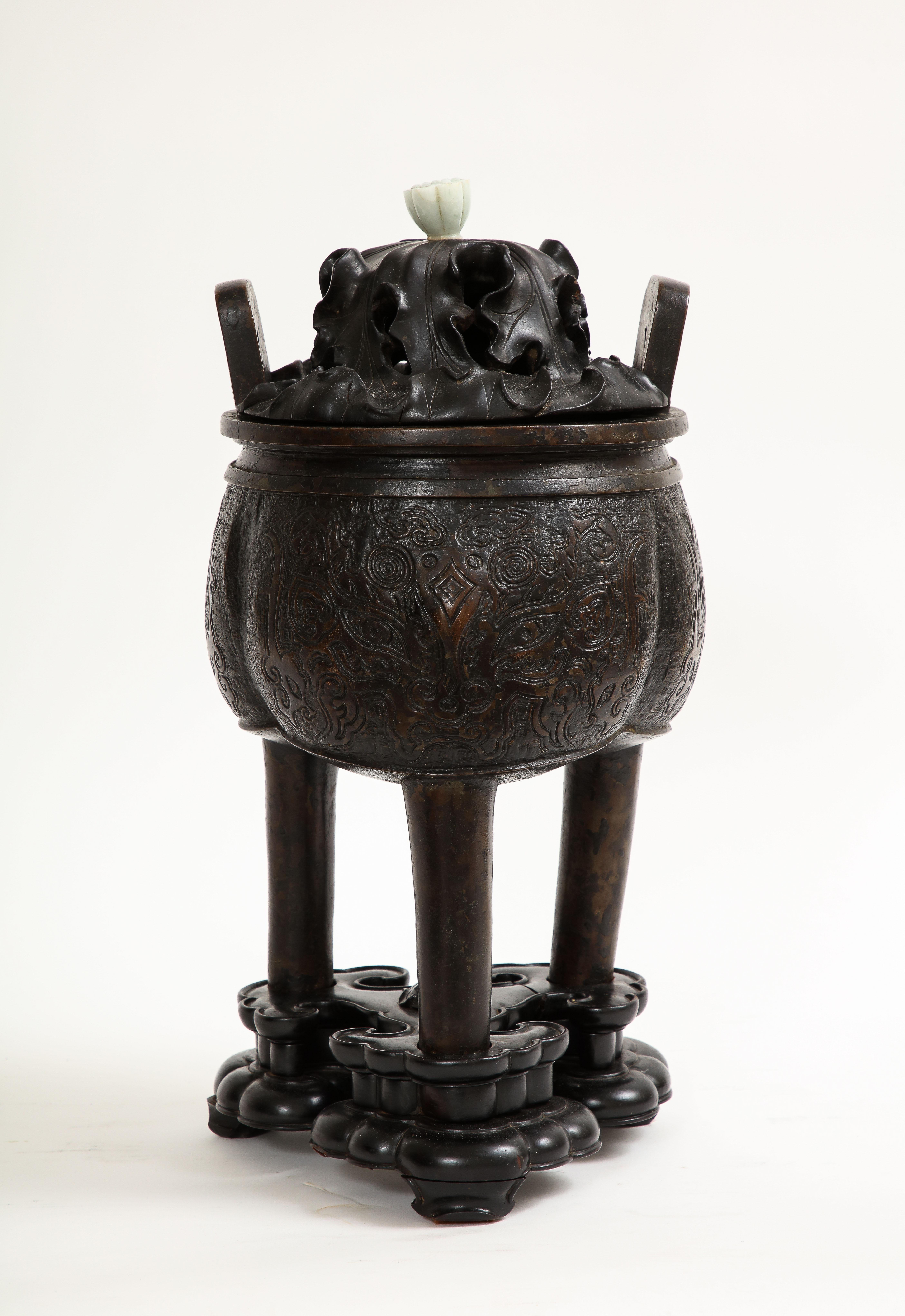 Fantastique et rare encensoir et couvercle en bronze patiné chinois du XVIIe siècle, avec fleuron en jade et base en bois.  Le corps de ce censeur est minutieusement décoré de motifs archaïques en relief ciselé à la main.  Le couvercle en bois est
