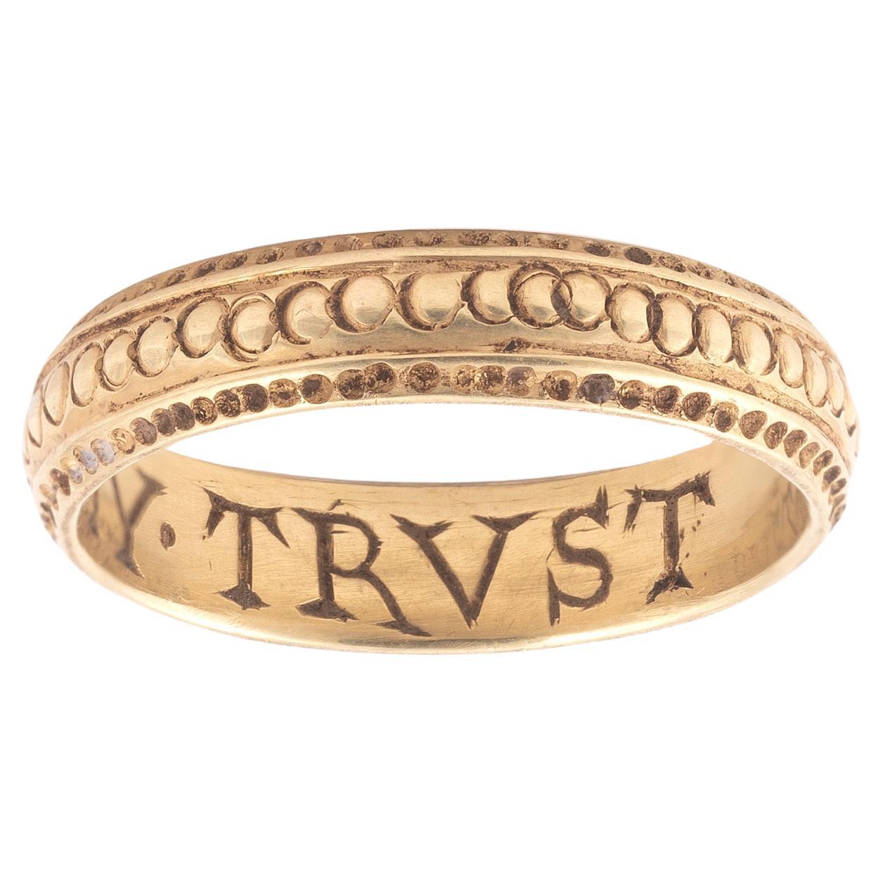 Late 17th century gold posy ring, engraved to the interior with the inscription 'Alle my trust' with engraved decoration to outer shank, size 7
Weight: 4,11gr.

“Posy rings,” their name deriving from the term poésie or poetry, are rings with mottoes