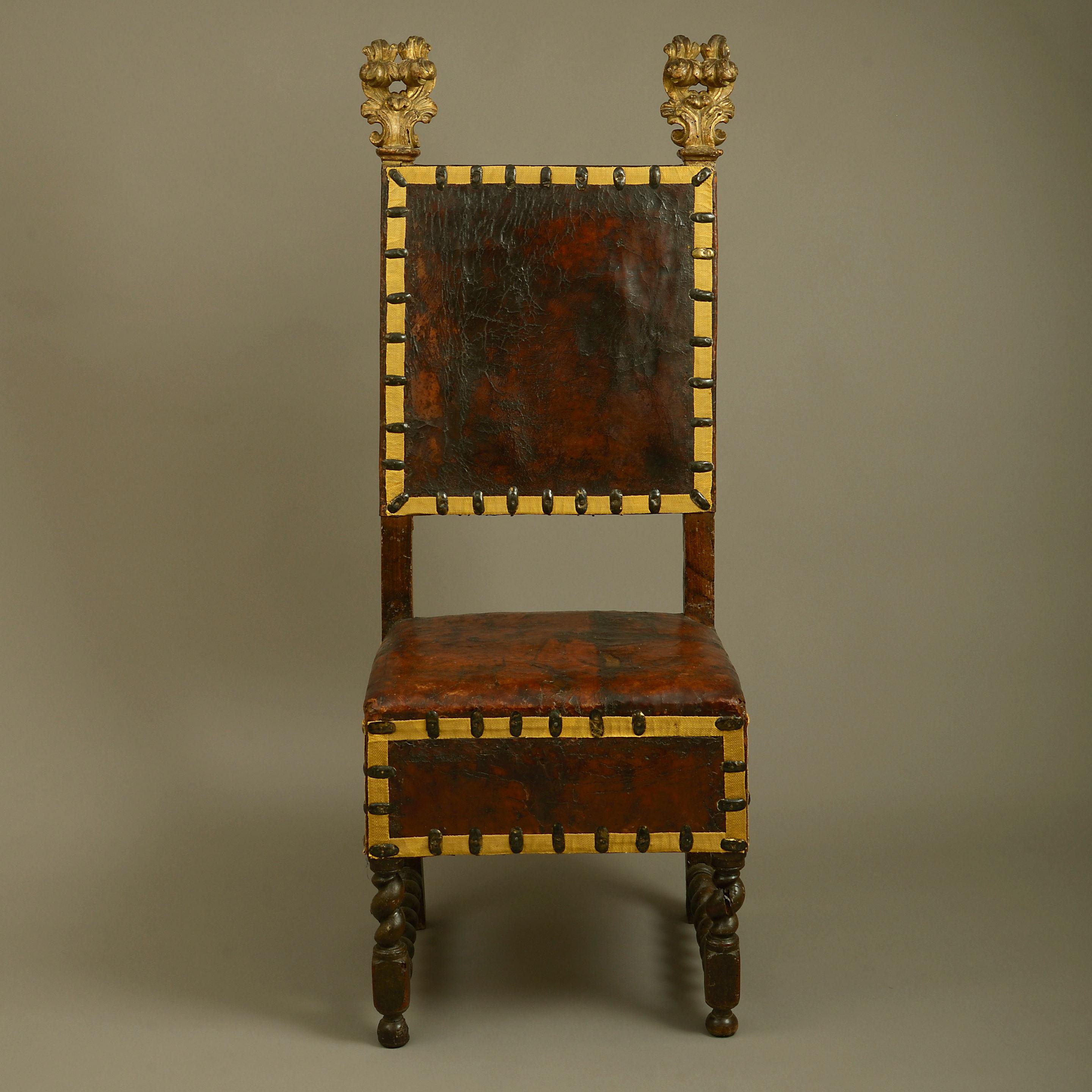 A rare mid-17th century Florentine walnut chair, of walnut, having gilded foliate finials and, retaining the original leather upholstery and raised on turned barley twist legs and side stretchers.
