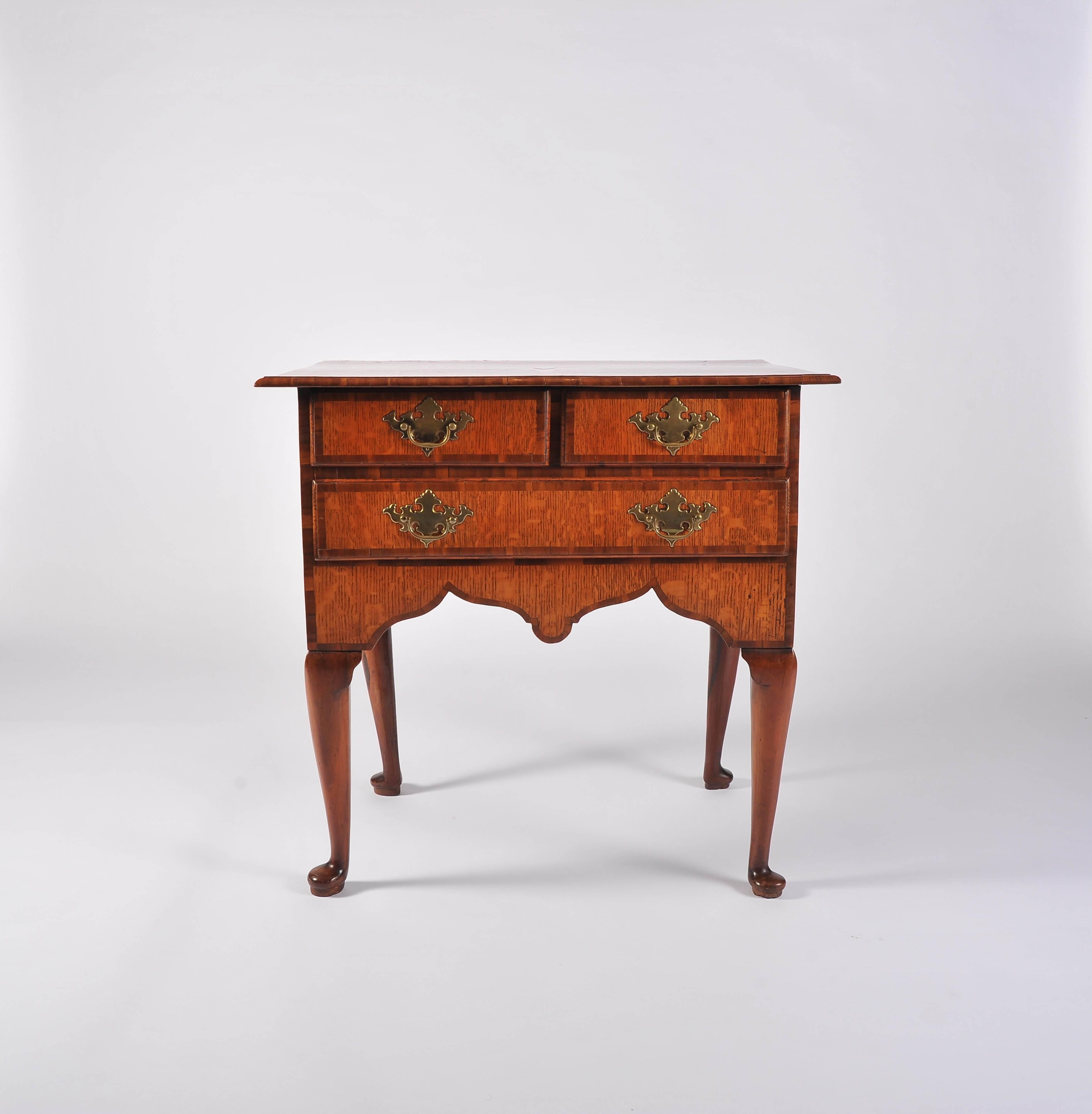 The overhanging top with boxwood and lignum inlaid star and elm and lignum cross banding, above two short and one long drawer. The drawers and front with shaped apron of pollarded oak with lignum cross banding, the cabriole legs of