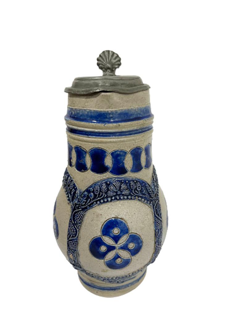 A 17th/ early 18th century German Westerwald Salt Glazed Stoneware jug

A German Westerwald jug with pewter lid. The salt-glazed stoneware jug with handle from Nassau has 4 circles intertwined in the middle in circled edges of grape vines and