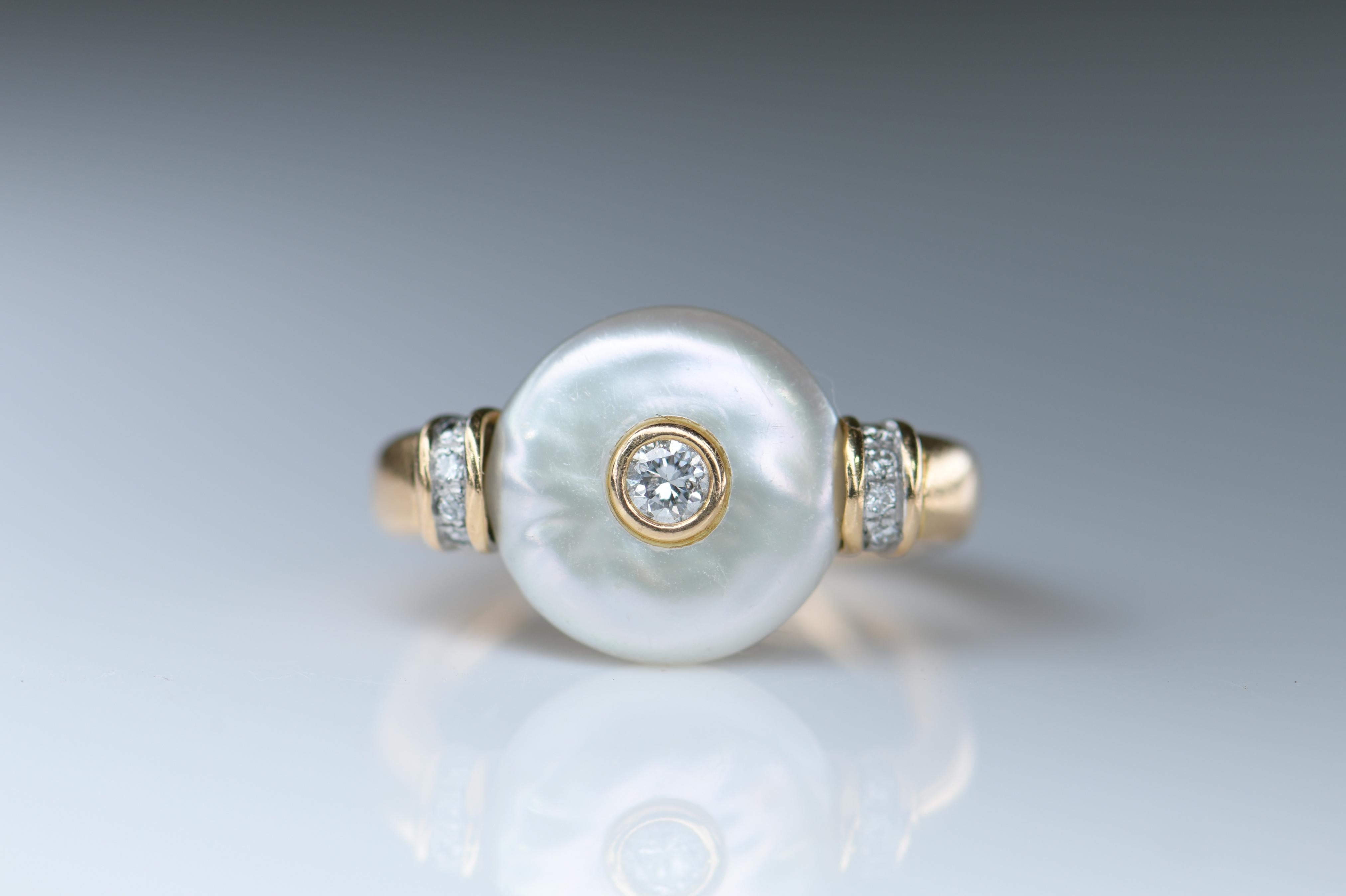 A pearl diamond ring set with bouton pearl, collet set to the centre with a small round brilliant-cut diamond, the ring with four small round brilliant-cut diamonds to each shoulder, stamped 750

It is currently a size I (UK), 4.25 (US), and can be