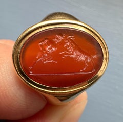 A 18k signet ring set with a Grand Tour carnelian intaglio. Pan fighting a goat.