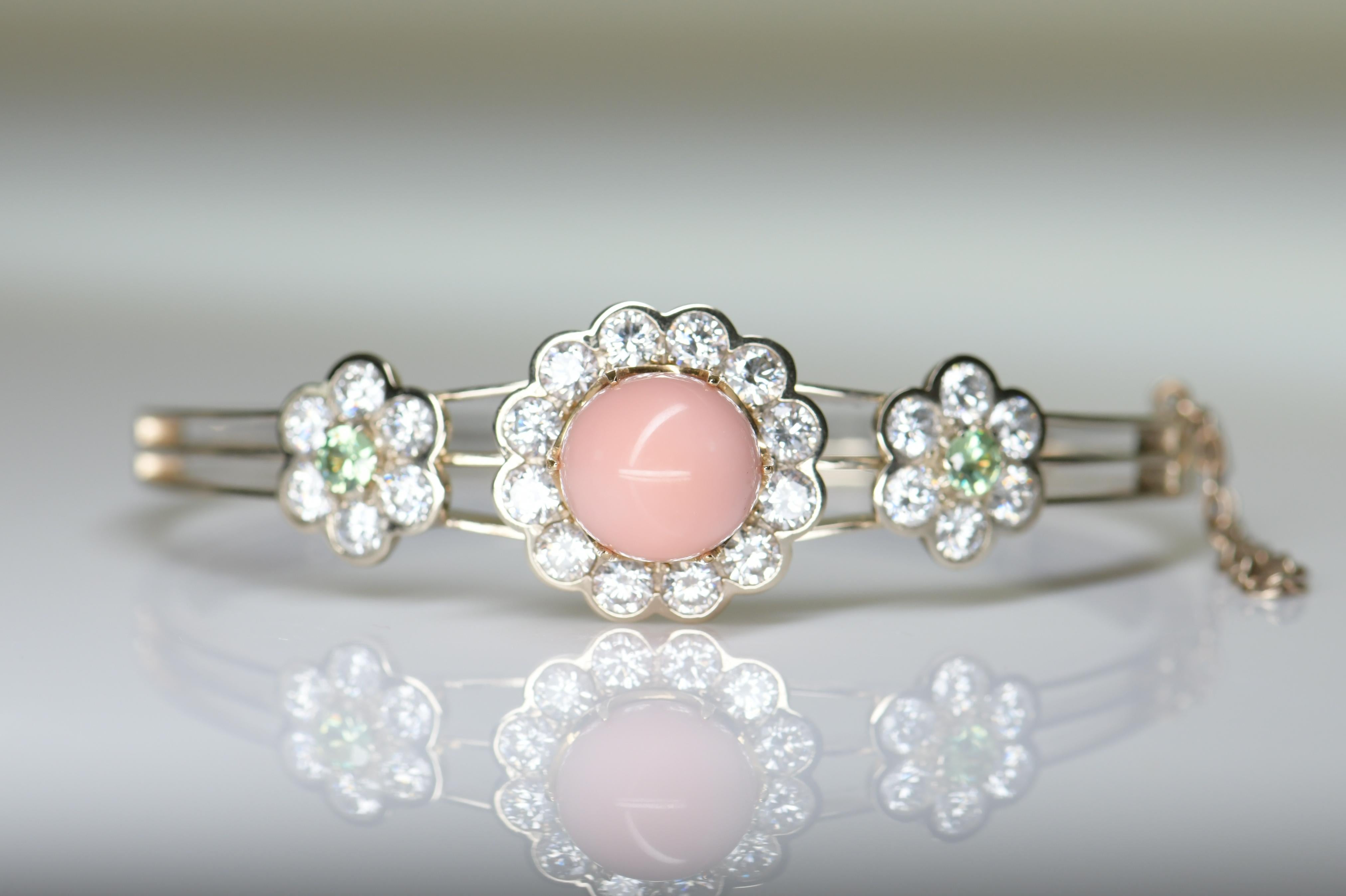 The stunning bangle of hinged design, set with a detachable conch pearl framed by circular-cut diamonds, flanked by demantoid garnet and diamond flower details, inner circumference 160mm, with ring fitting enabling conch pearl to be worn as a ring,