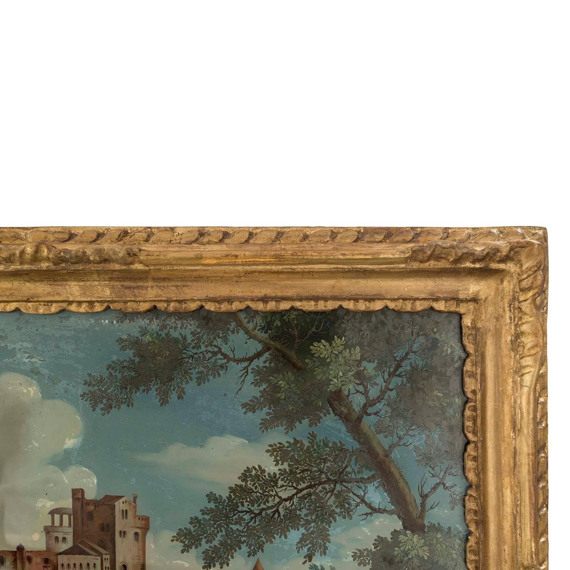 A very decorative 18th century Venetian reverse painted on glass. The painting is of a landscape with figures next to a river, some pulling a fishing net while others are conversing and fixing a fence. The landscape leads to the town's medieval