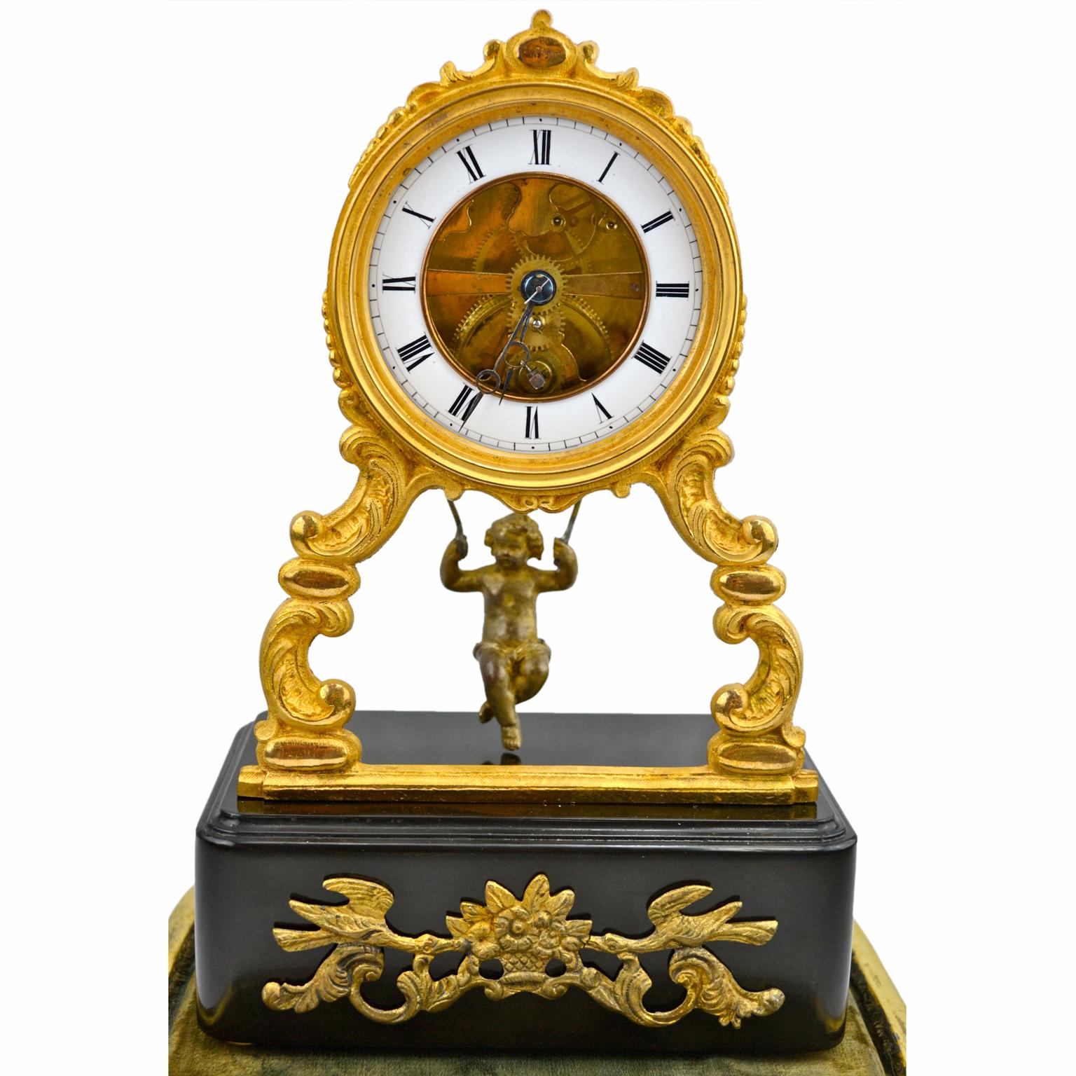 A late 19th century French swinging putto ‘mystery’ clock. The clock drum has a gilded bronze bezel and is supported on two scrolling front legs which are supported on a rectangular ebonized base with a front gilded mount. The white enamel chapter