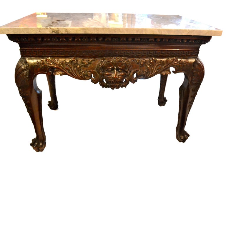 A finely carved Irish Chippendale style mahogany center hall table (or server), both long sides centered with large growling lions heads below Greek key and egg and dart moldings, the four legs with shell carving to the tops, tapering to large hairy