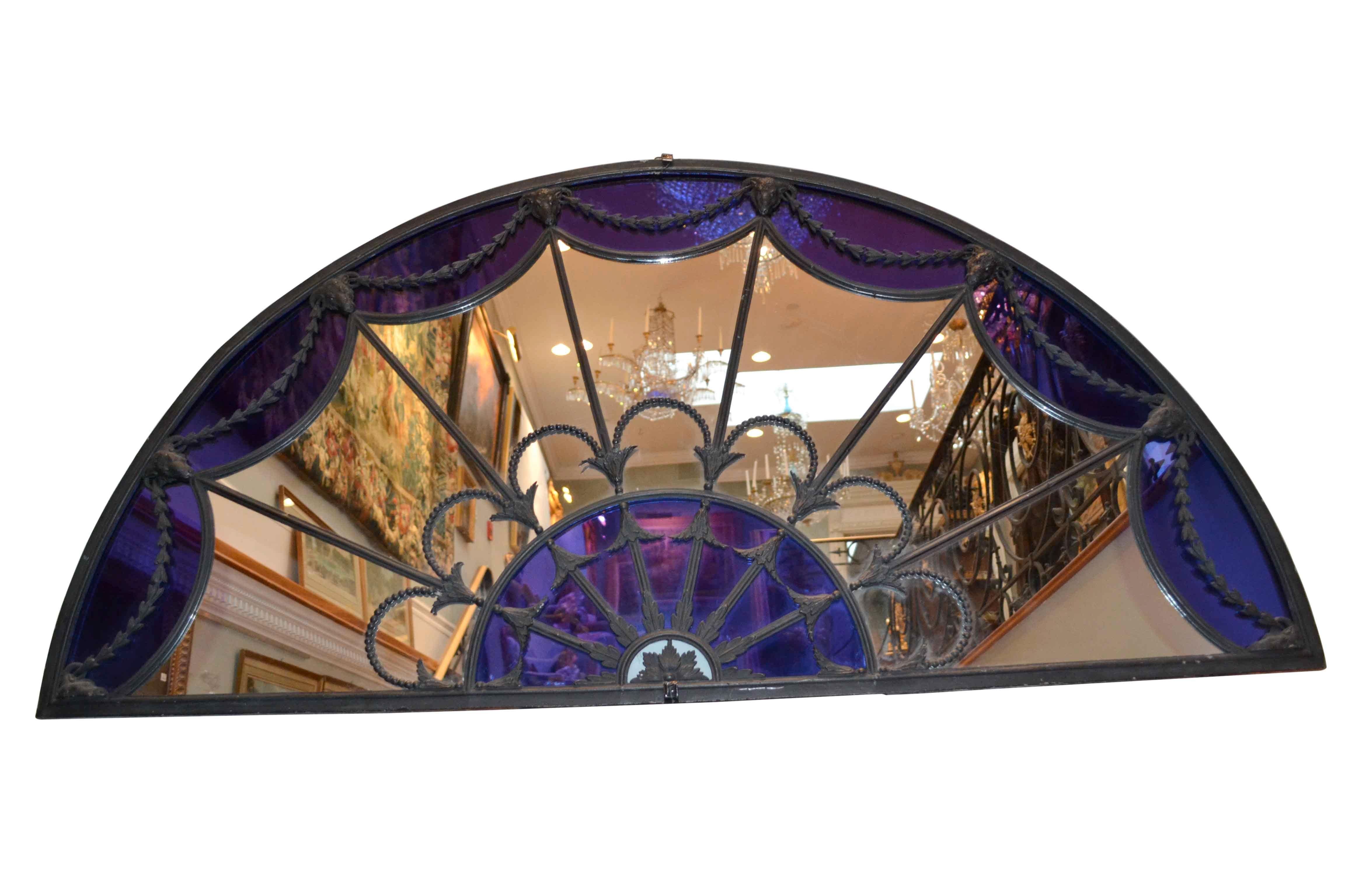 A period Georgian (Irish) over door semi circular transom mirror with modern blue glazing in the full Adam style, framed with iron and cast metal swags and goat’s heads.
