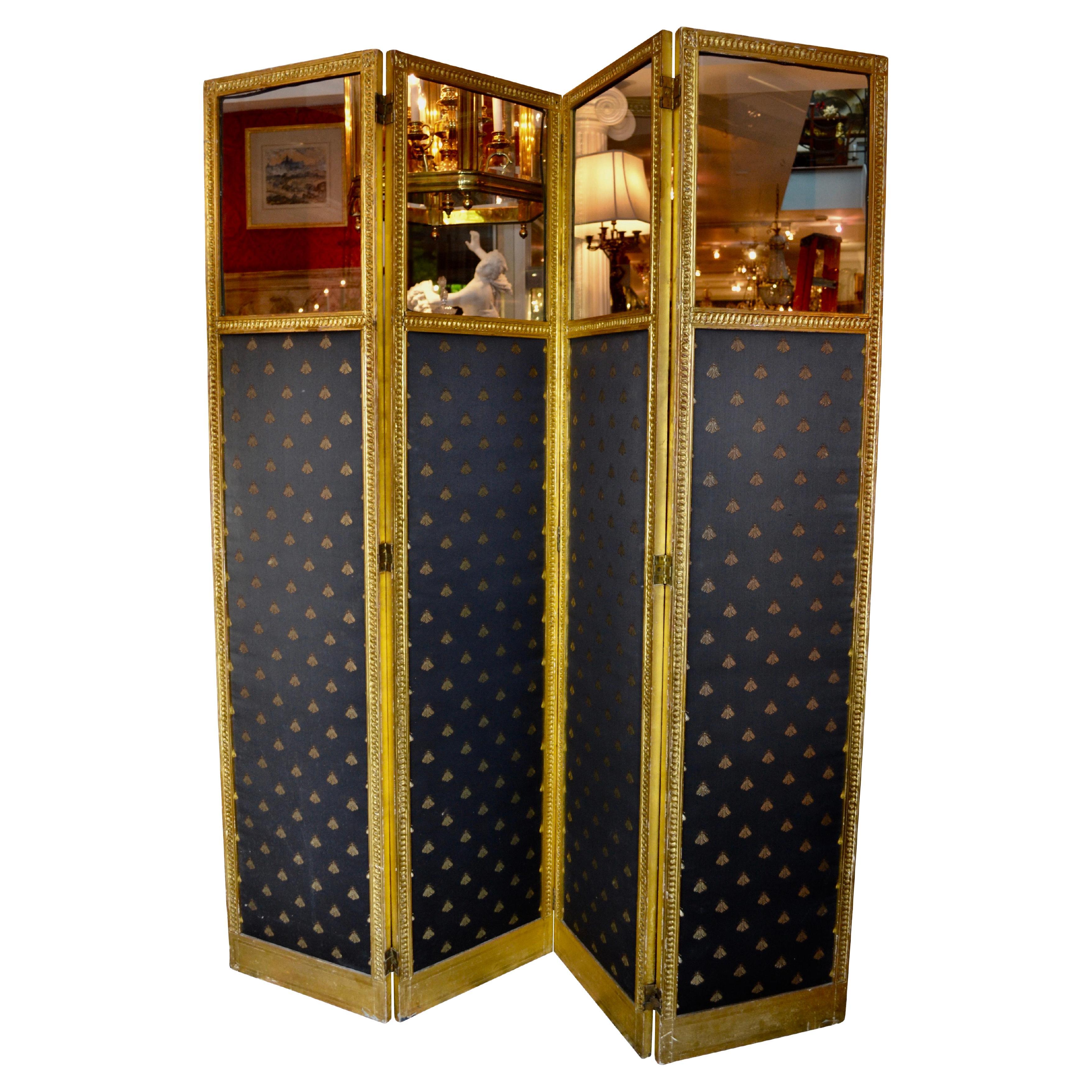 An attractive four panel screen having clear glass panels to the tops of each panel. The frames are of carved and gilded wood decorated with interlacing circles; the bottom three quarters of each panel are upholstered in a black Empire design fabric