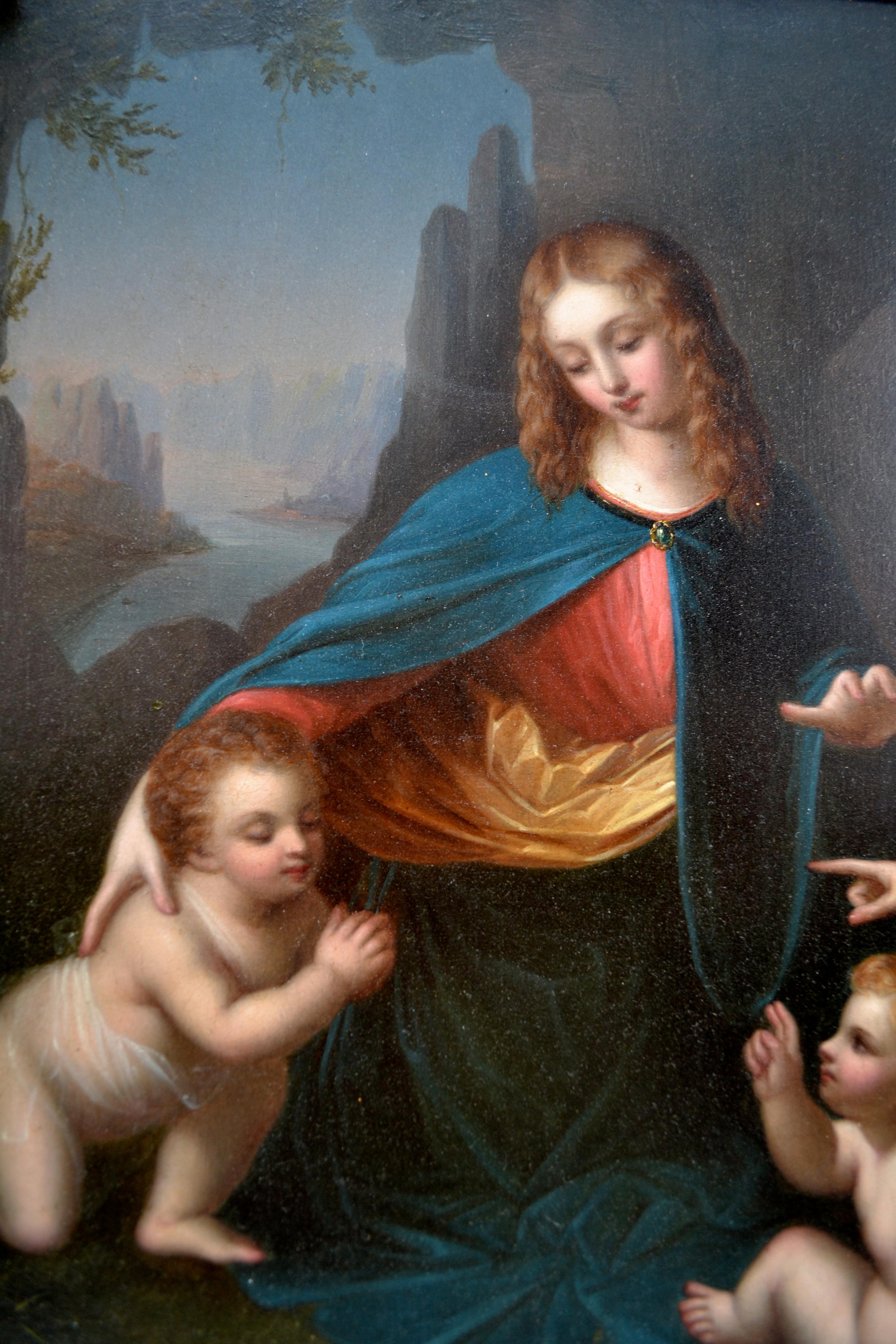 An early 19th century oil on board depicting the beautiful young Madonna and child Jesus with the infant John the Baptist and an angel, in a rocky setting. The painting is in a carved and gilded frame of the period. The original work on which this