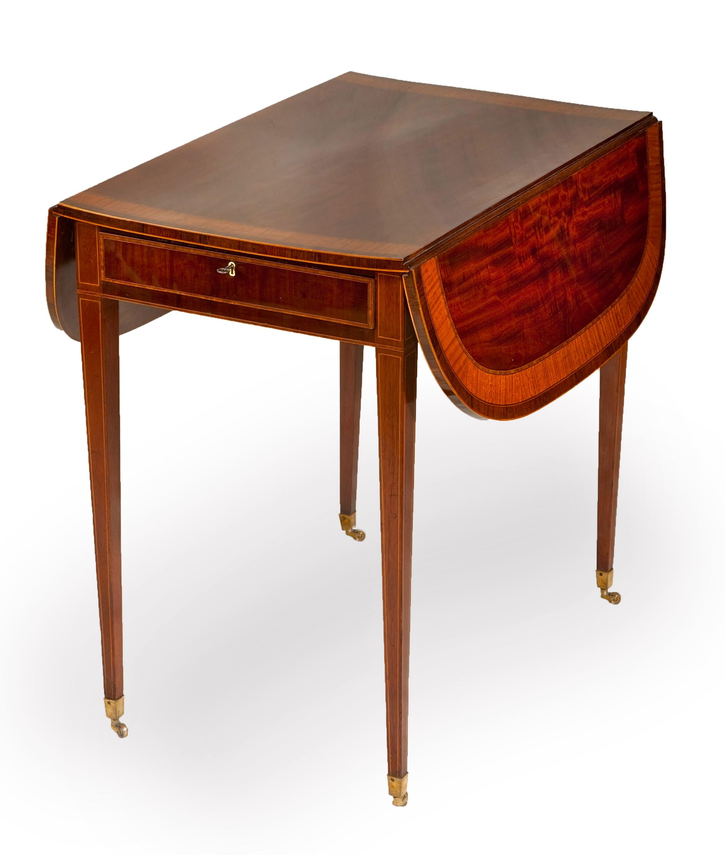 A Classic Pembroke table made of flame mahogany with satinwood and  tulip wood banding; single drawer to one side with lock and flaps on either side that can be raised by brackets on hinges (known as “elbows”) to increase its size. The table is