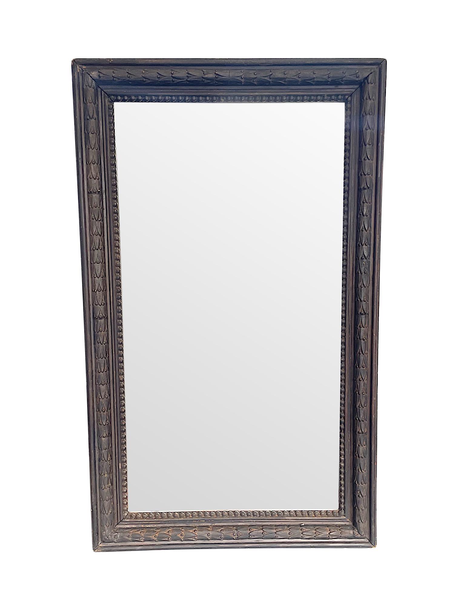 A 1900s French ebonzied Acanthus leaf mirror with moulded gesso acanthus leaf design set within a rectangular solid wood frame, with inside beaded wooden edge with original plate and solid wooden back. A well made piece, full of orignal character
