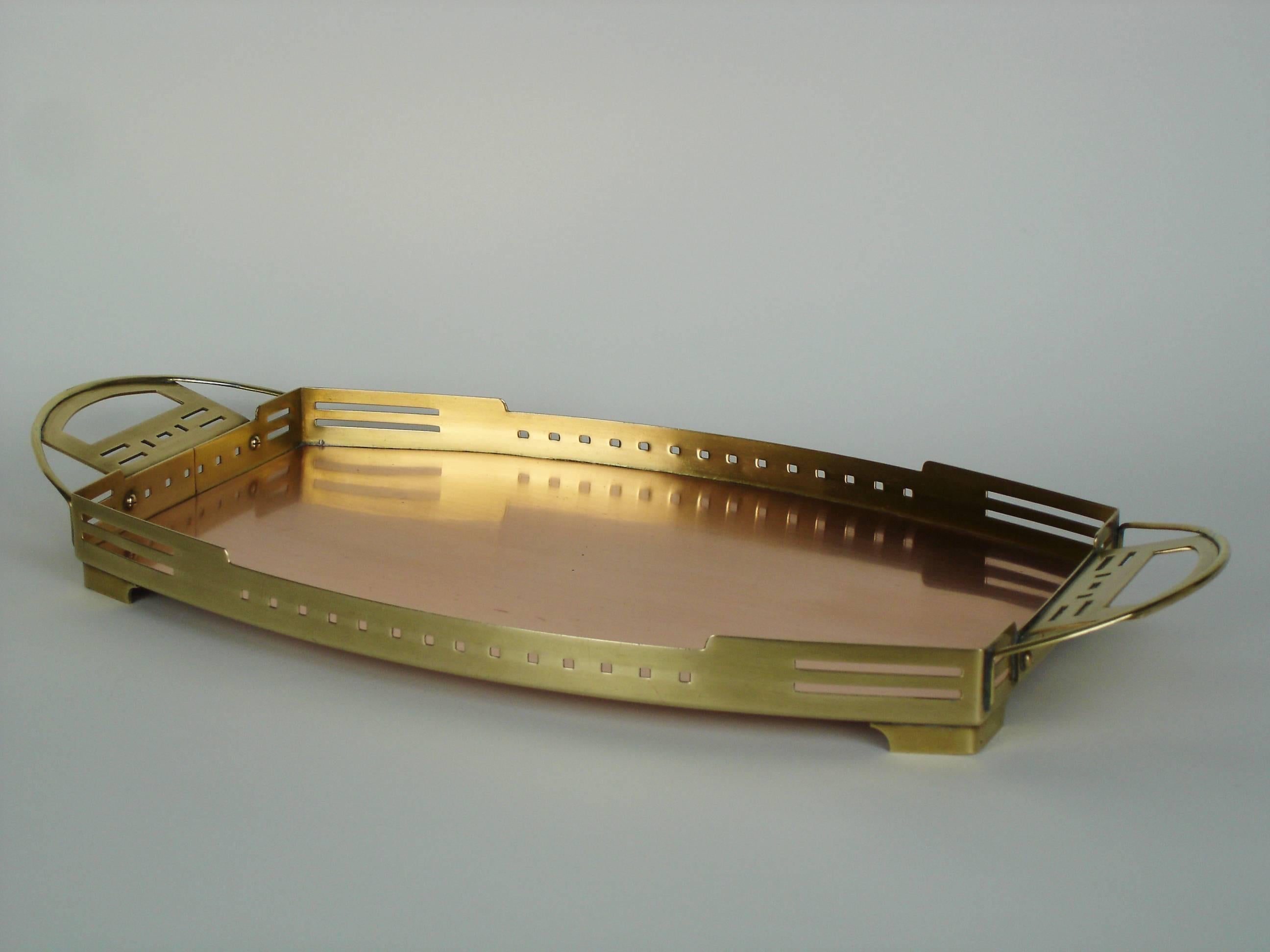 A rounded rectangular brass and copper tray with a pierced gallery and handles.