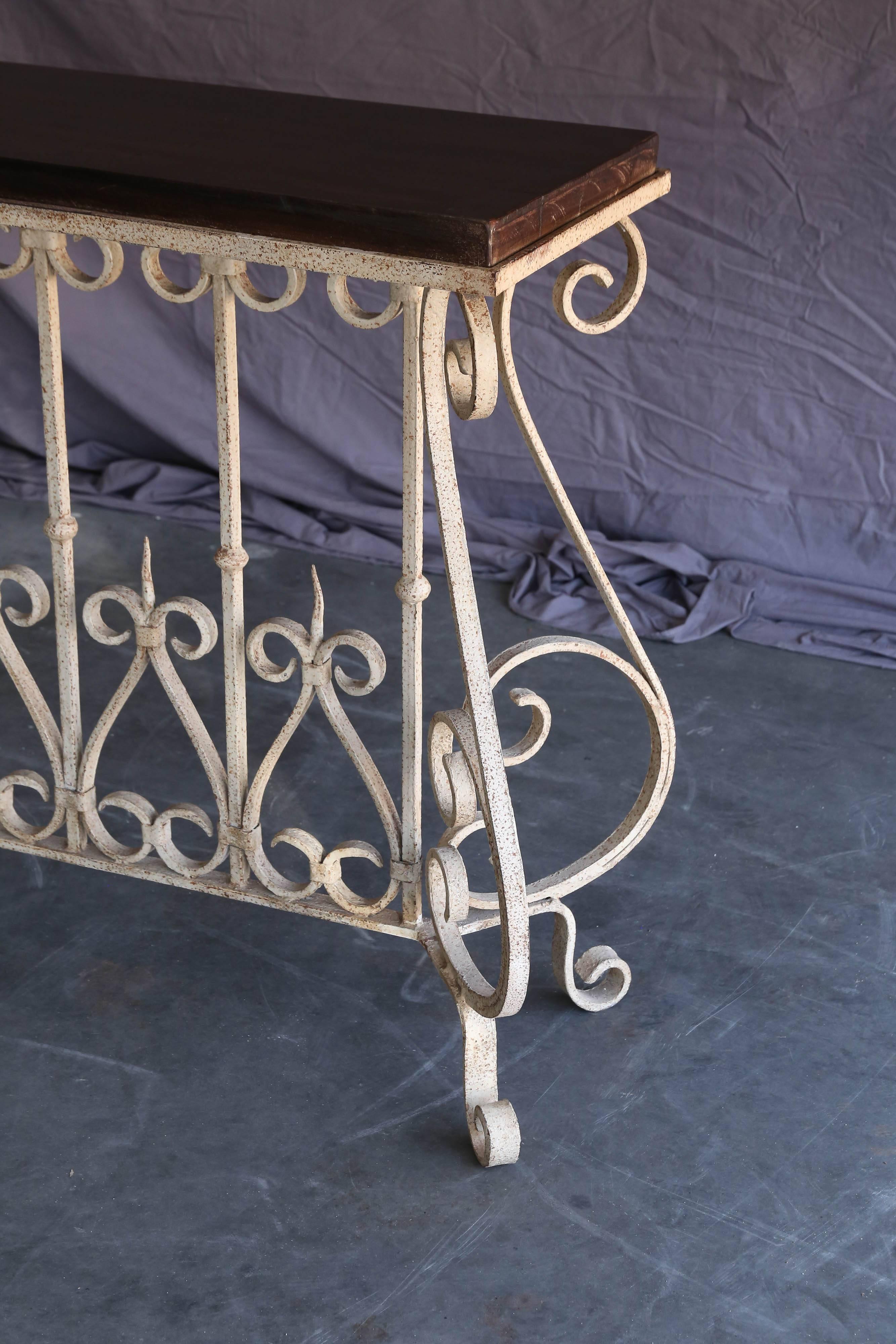An early 20th century French colonial handcrafted console table from a settler's home in India.
The top is made of solid teakwood and the support is hand forged wrought iron. The design of the ironwork comes from country furniture from France. This