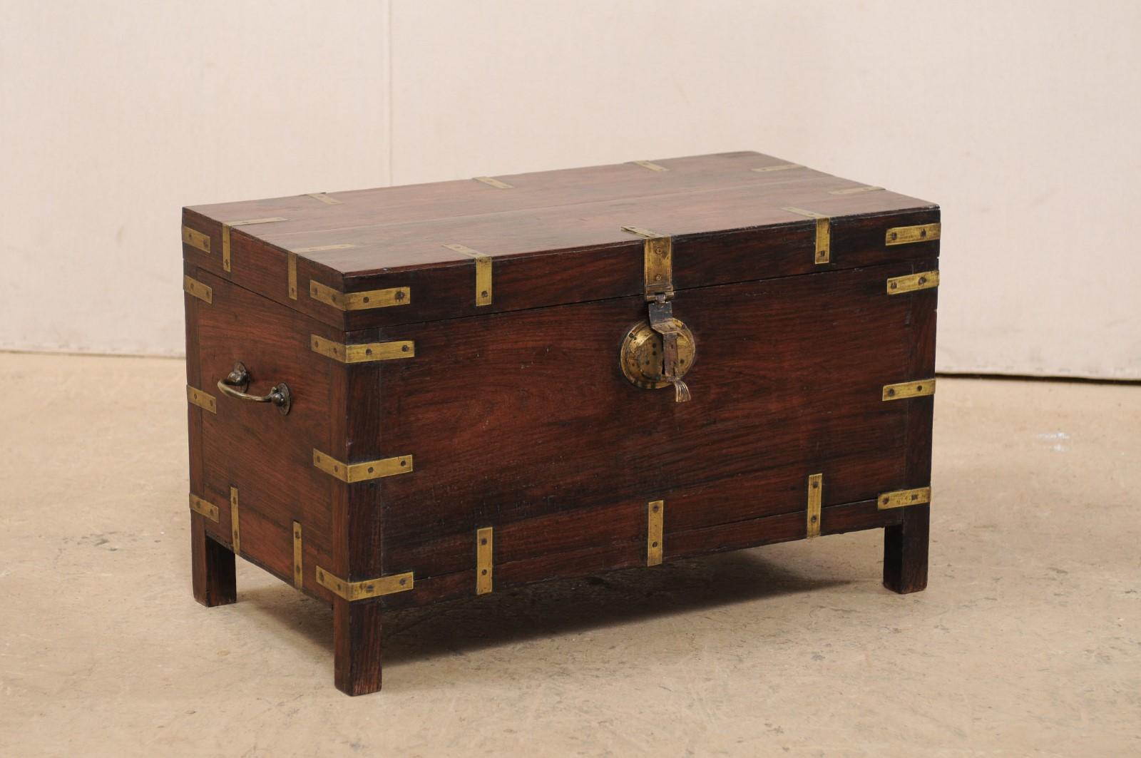 A British Colonial rosewood trunk from the 1920s, which would also function beautifully as a small coffee table. This antique British Colonial keep-sake trunk of beautiful rosewood, has been nicely adorn with brass L-bracket wraps about all of it's