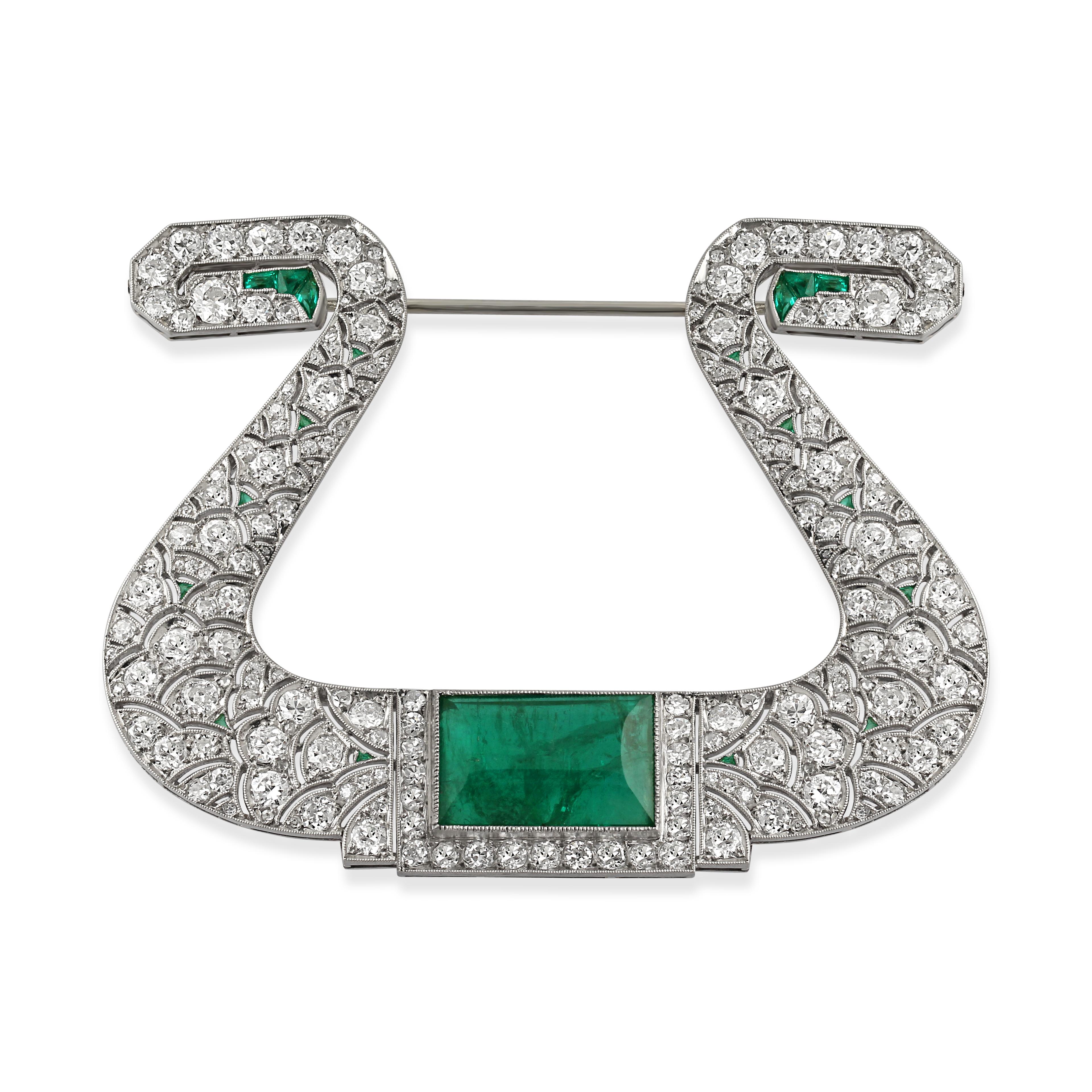 A platinum, diamond & emerald horseshoe brooch. Set with a step-cut emerald surrounded by single and circle-cut diamonds and highlighted by calibré-cut emeralds. Origin: French, with unknown maker's marks. Circa 1920s.
