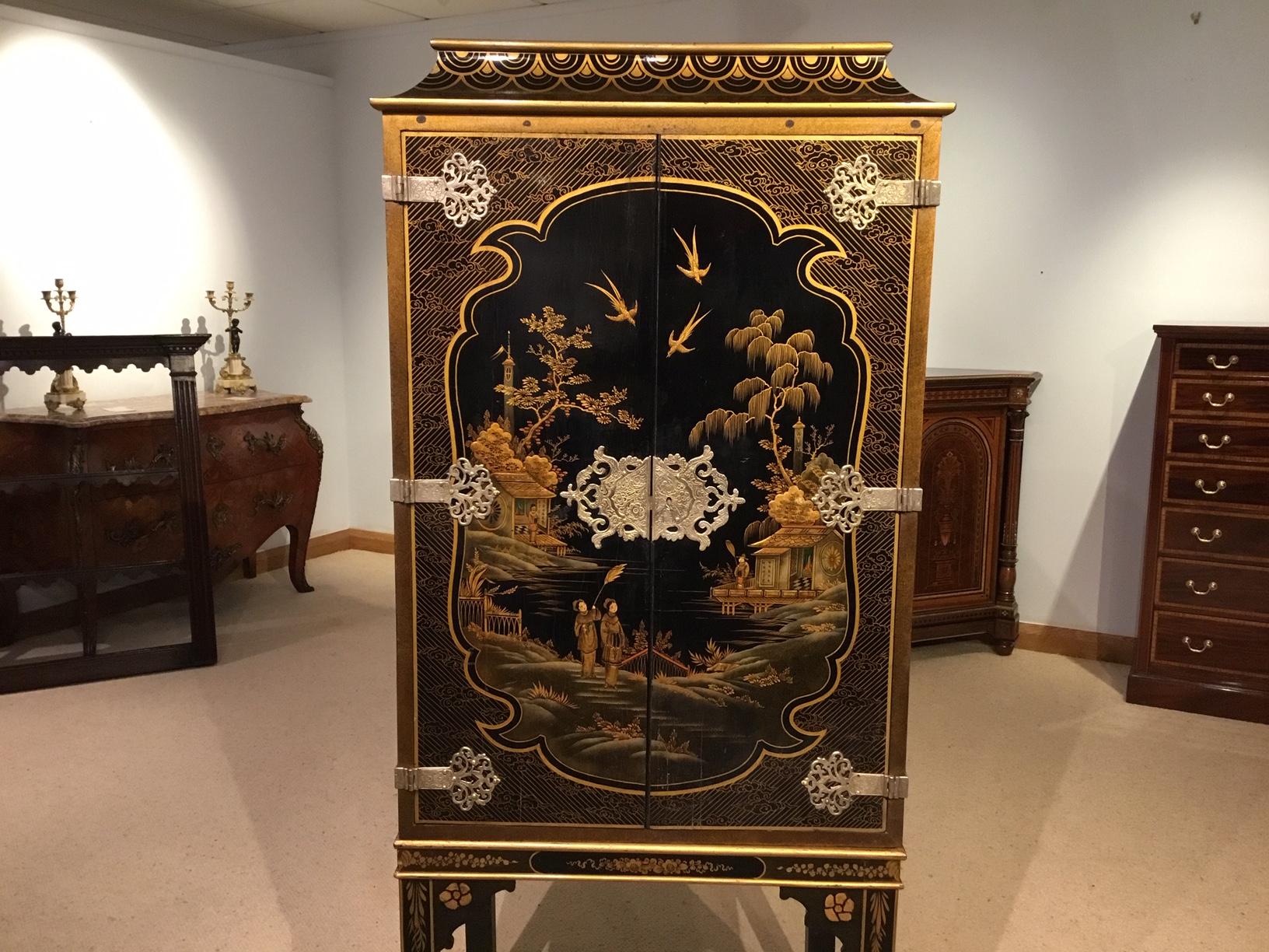 A 1920s period chinoiserie cabinet. Having a pagoda top with chinoiserie detail above the twin lacquer and chinoiserie doors with silver plated filigree hinges and escutcheons, opening to reveal a shelf interior, supported on a square chinoiserie