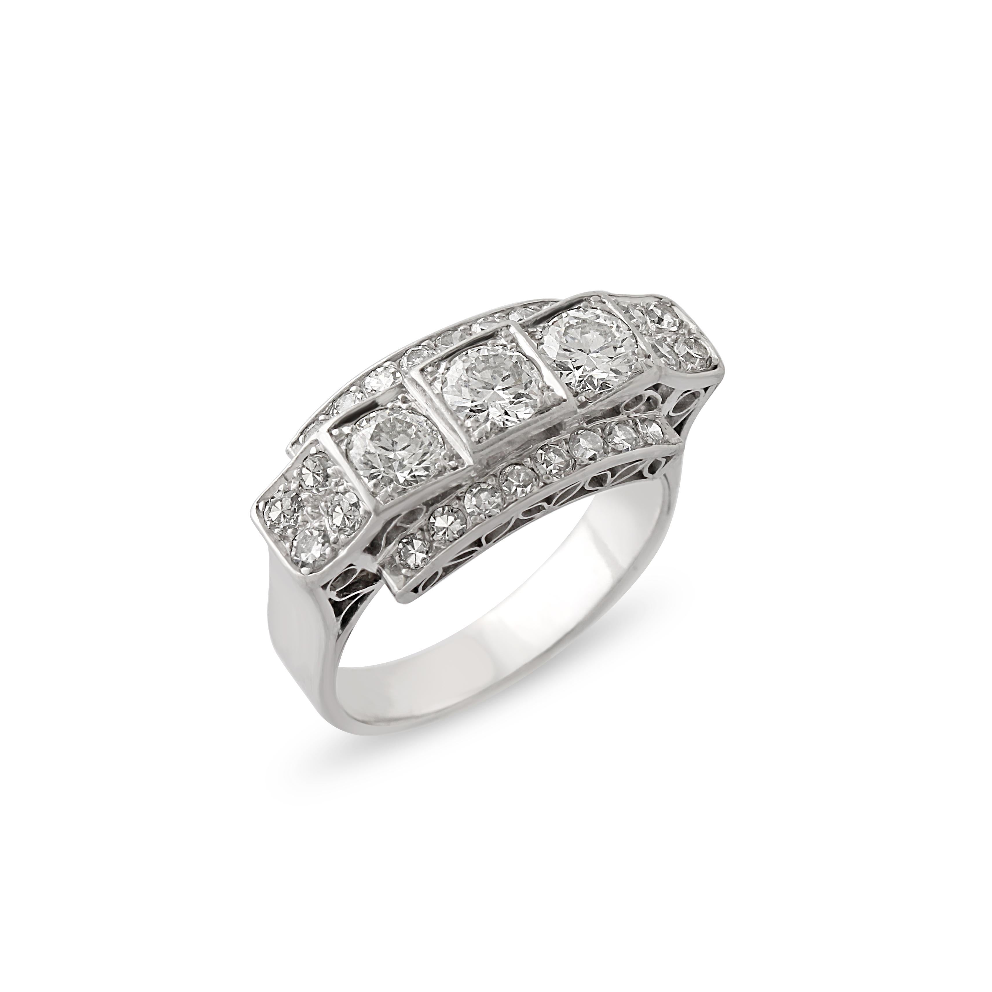 A 1920s platinum and diamond cocktail ring. Set with single and circle-cut diamonds, with a line of five stones in the centre bordered by a shorter row of smaller diamonds either side with beautiful open gallery work on shank. Size = P.
