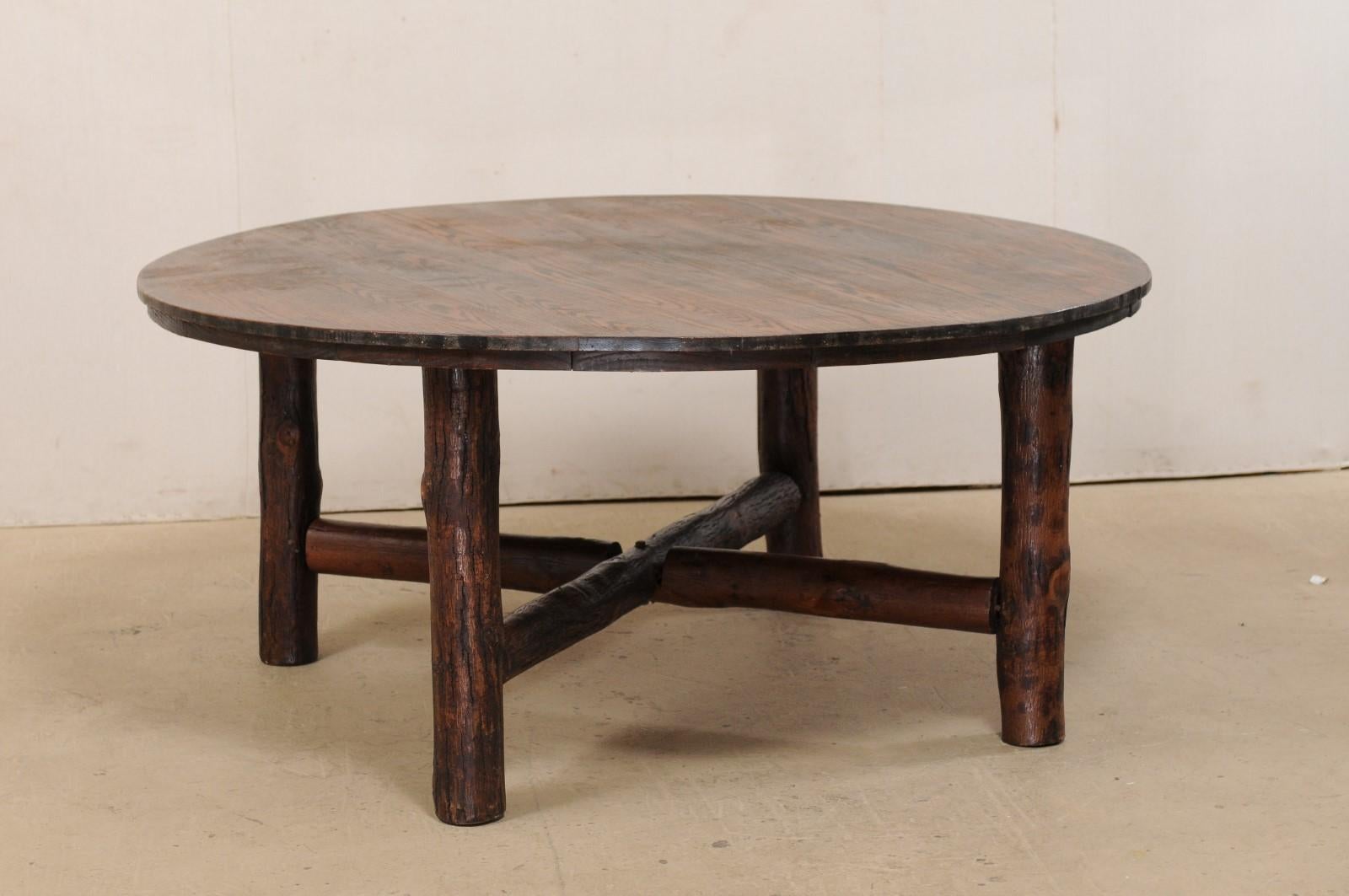 A beautifully rustic American Old Hickory round table with cross X-stretcher from the 1920s. This antique Old Hickory table is a rare style, and features a round top which is almost 5.5 feet in diameter, and is raised upon four sturdy post legs,