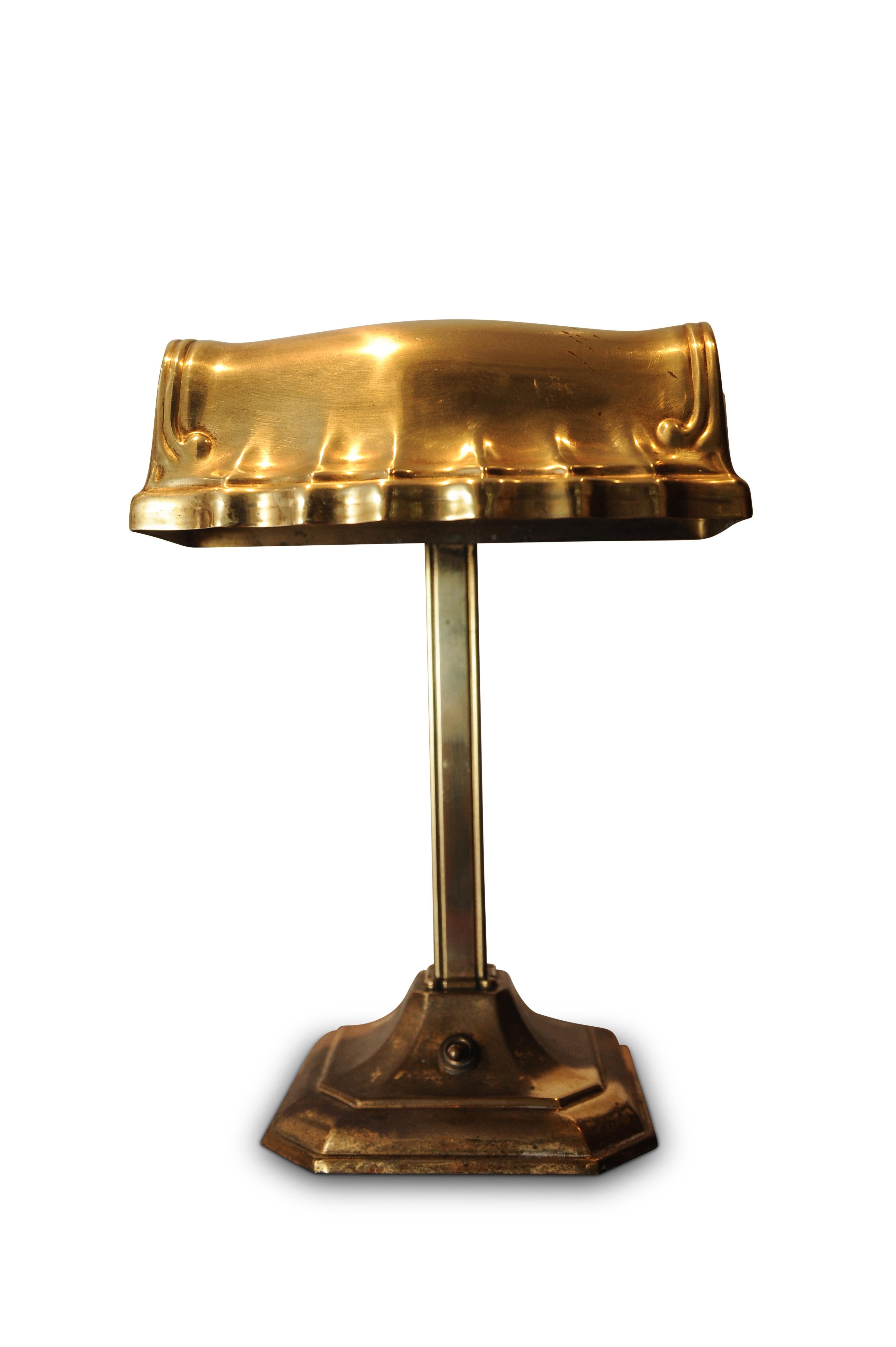 A good early 20th century solid brass adjustable bankers desk lamp, raised on a terraced square base and brass shade atop, with original fittings and switch.
Excellent patina to the brass.

Item has been tested and Pat Tested to UK