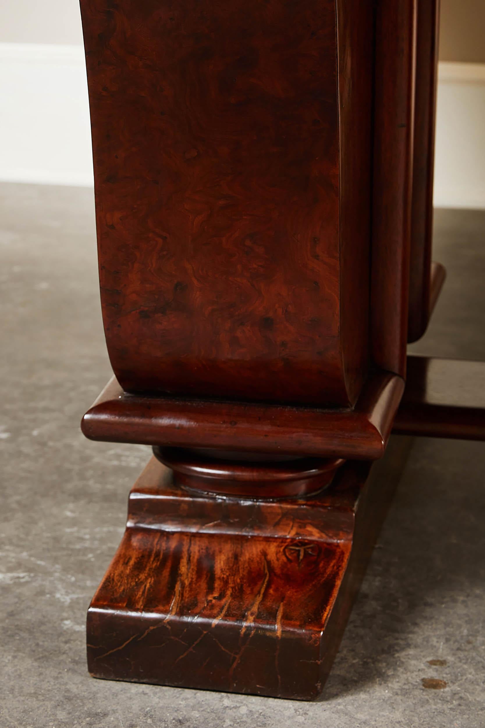 An elegant Art Deco dining table made in French Indo-China for the local expatriate market. The rectangular top of curly-grained burl rosewood, with a slightly projecting molding along the lower edge, echoed in the moldings of the S-curved panel