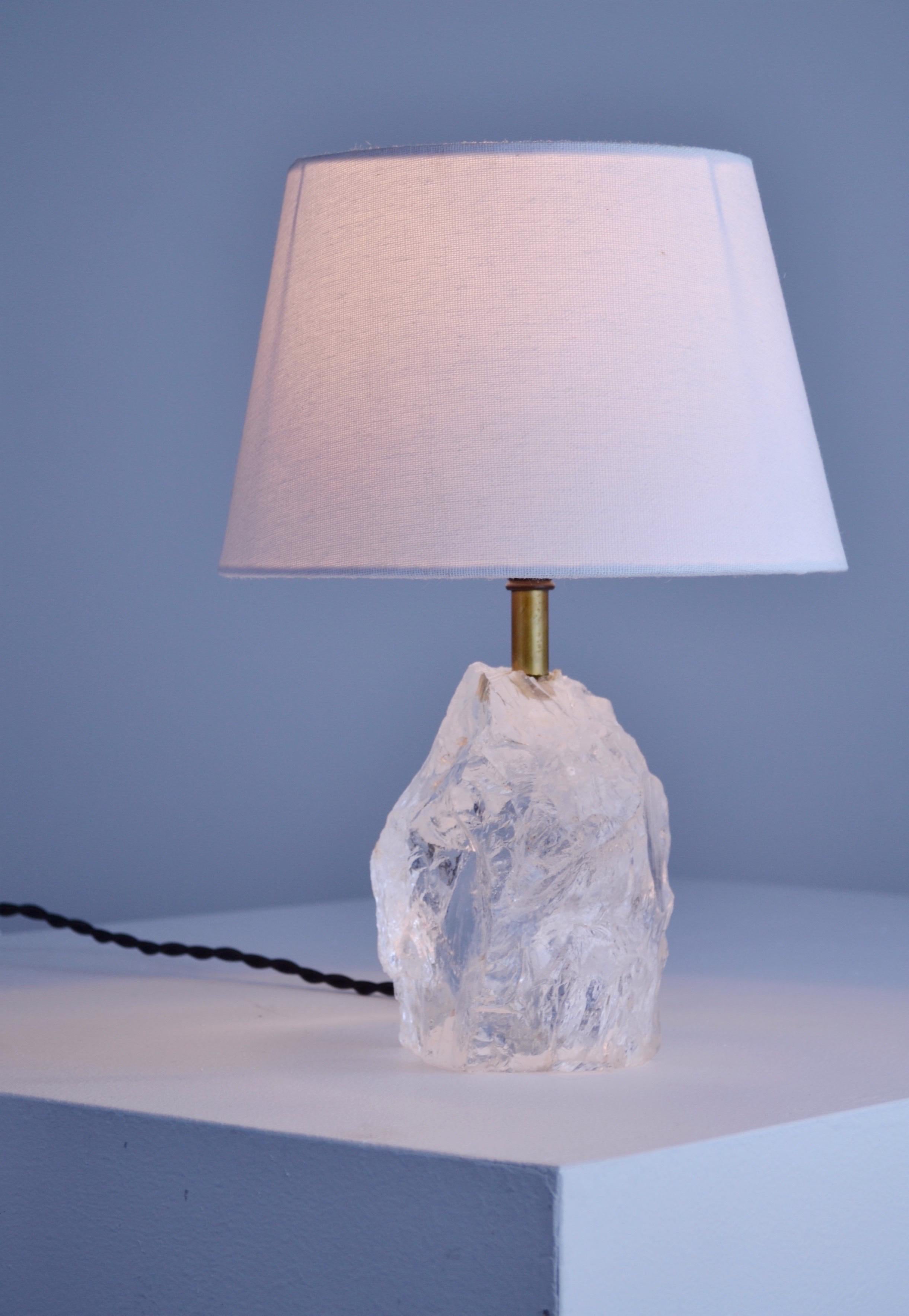 A 1930s lamp composed of a block of rock crystal with a flat base for stability, adorned with elegant brass elements, designed in the style of Jean-Michel Frank's creations. This unique piece embodies the minimalist and refined aesthetic of the era,
