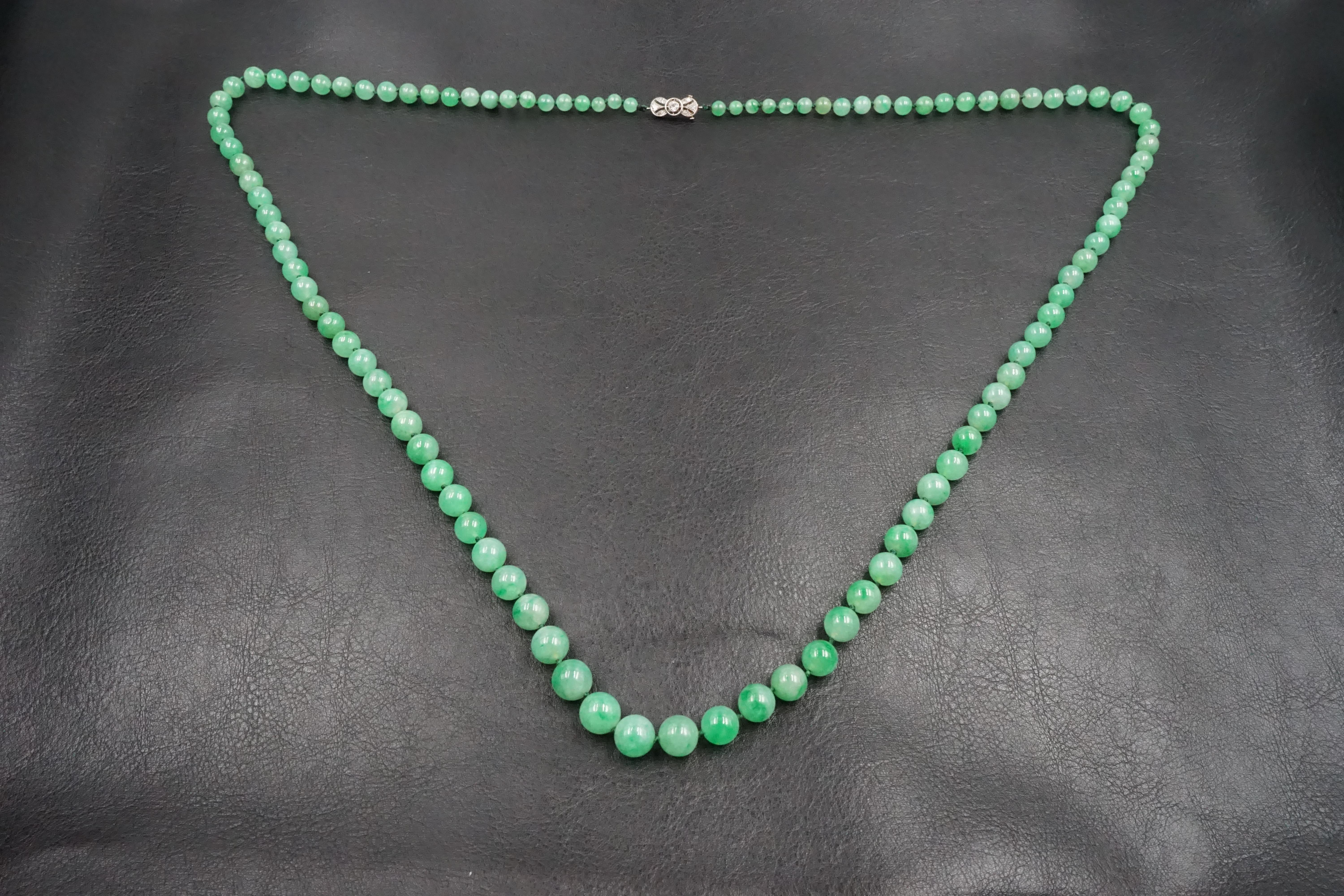 A beautiful natural translucent jadeite necklace. The platinum clasp features an old cut diamond in the centre and smaller diamonds around, a French assay marks on one side of the pin and maker's mark at the other side.

Length: 85cm 
Weight: 69.7g