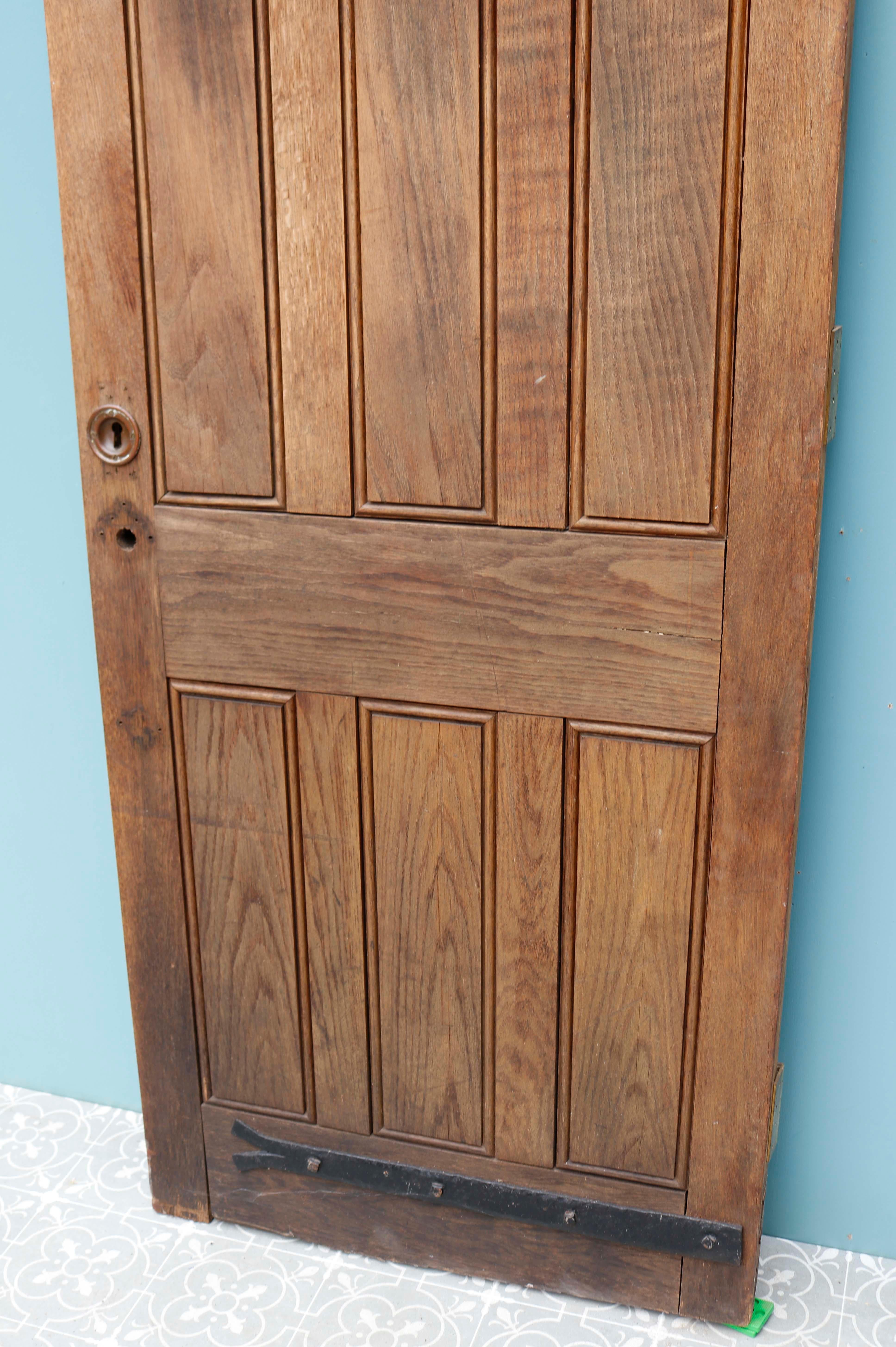 Puerta exterior de roble recuperado de 1930. Una puerta de roble macizo de principios del siglo XX. Con un tallado mínimo pero eficaz y detalles de hierro forjado, esta puerta exterior de gran resistencia aporta estilo además de funcionalidad.